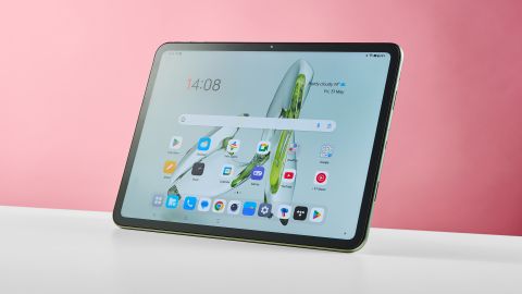 OnePlus Pad Go valkoisella pöydällä vaaleanpunaista seinää vasten