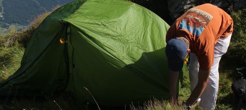 Camper pitching Exped Mira II HL tent on mountain