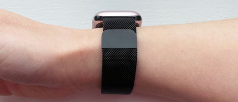 A black-coloured metal mesh watch strap wrapped around a woman&#039;s wrist.