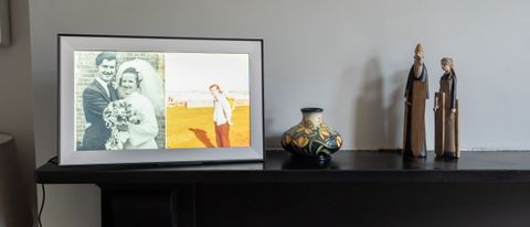 The DragonTouch Classic 15 Pro Photo Frame on a mantelpiece next to some ornaments