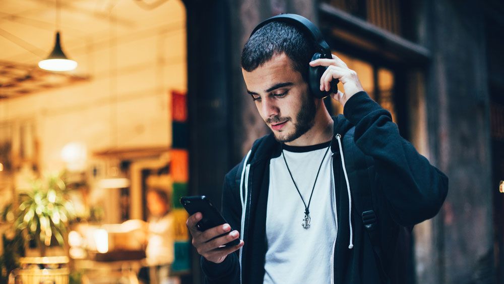 A young man listening to music through wireless headphones.