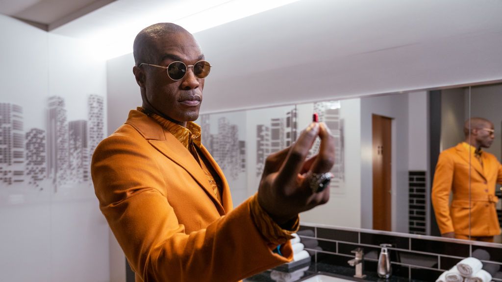 Actor Yahya Abdul-Mateen II on the set of "The Matrix Resurrections," wearing sunglasses and holding a red pill.Berlin, Germany, 2020.