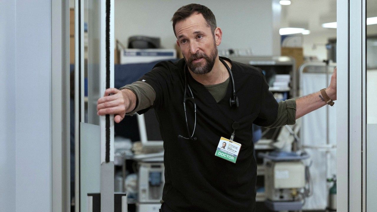 Actor Noah Wyle plays Dr. Michael "Robby" Robinovitch on the hit TV series The Pitt. He is in his scrubs in the ER.
