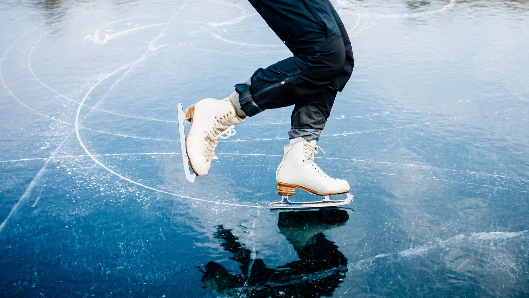 Feet in ice skates skate across a frozen lake.