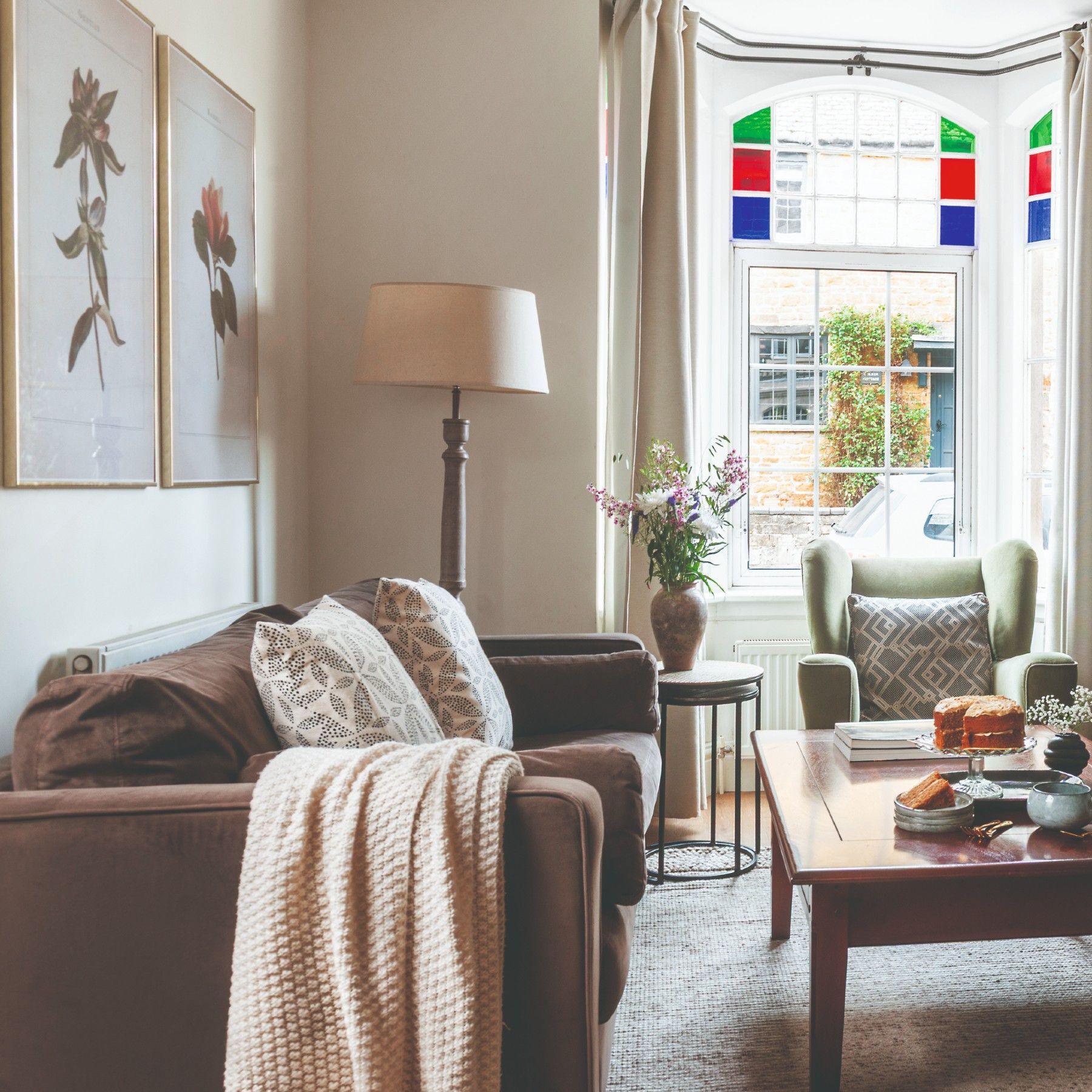 A small living room with a brown sofa, a green armchair and a built-in shelving painted black matching the fireplace