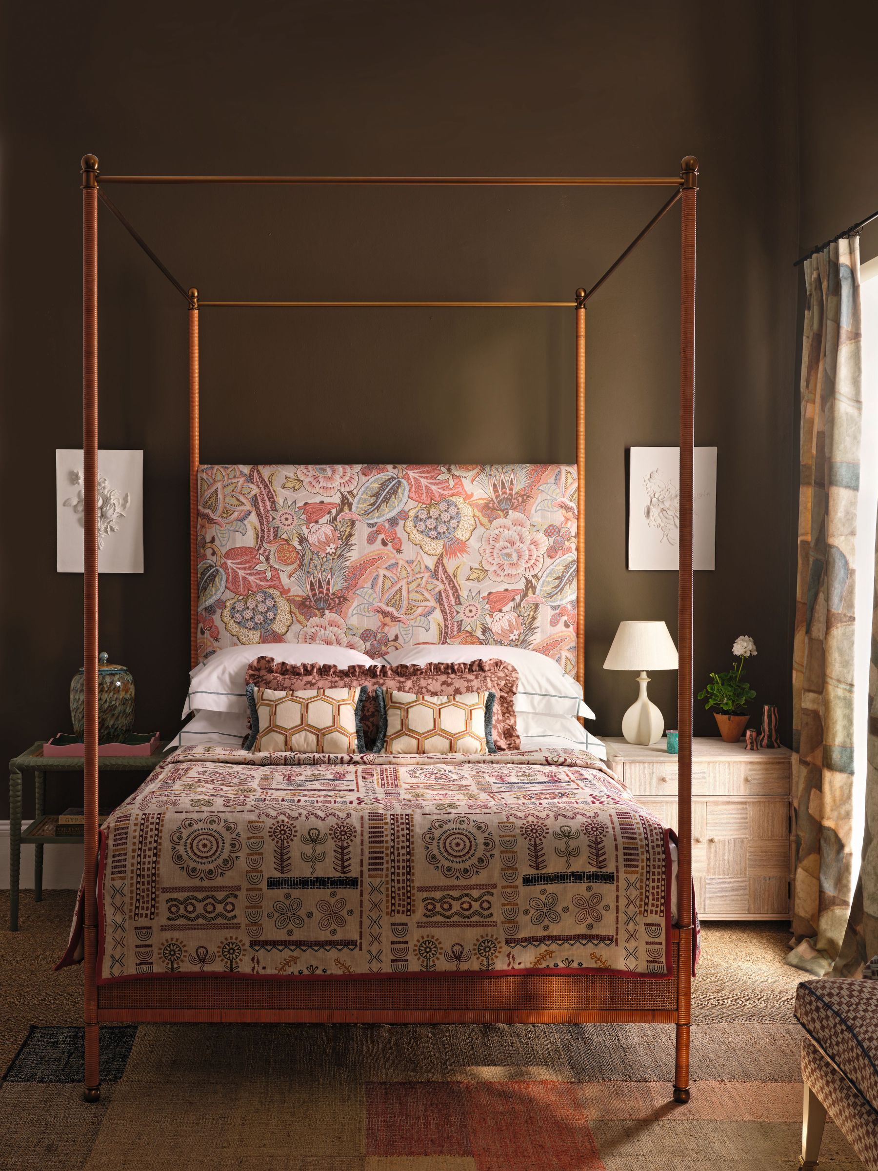 Bedroom with dark brown walls, four poster bed, floral headboard, geometric curtains and jute carpet
