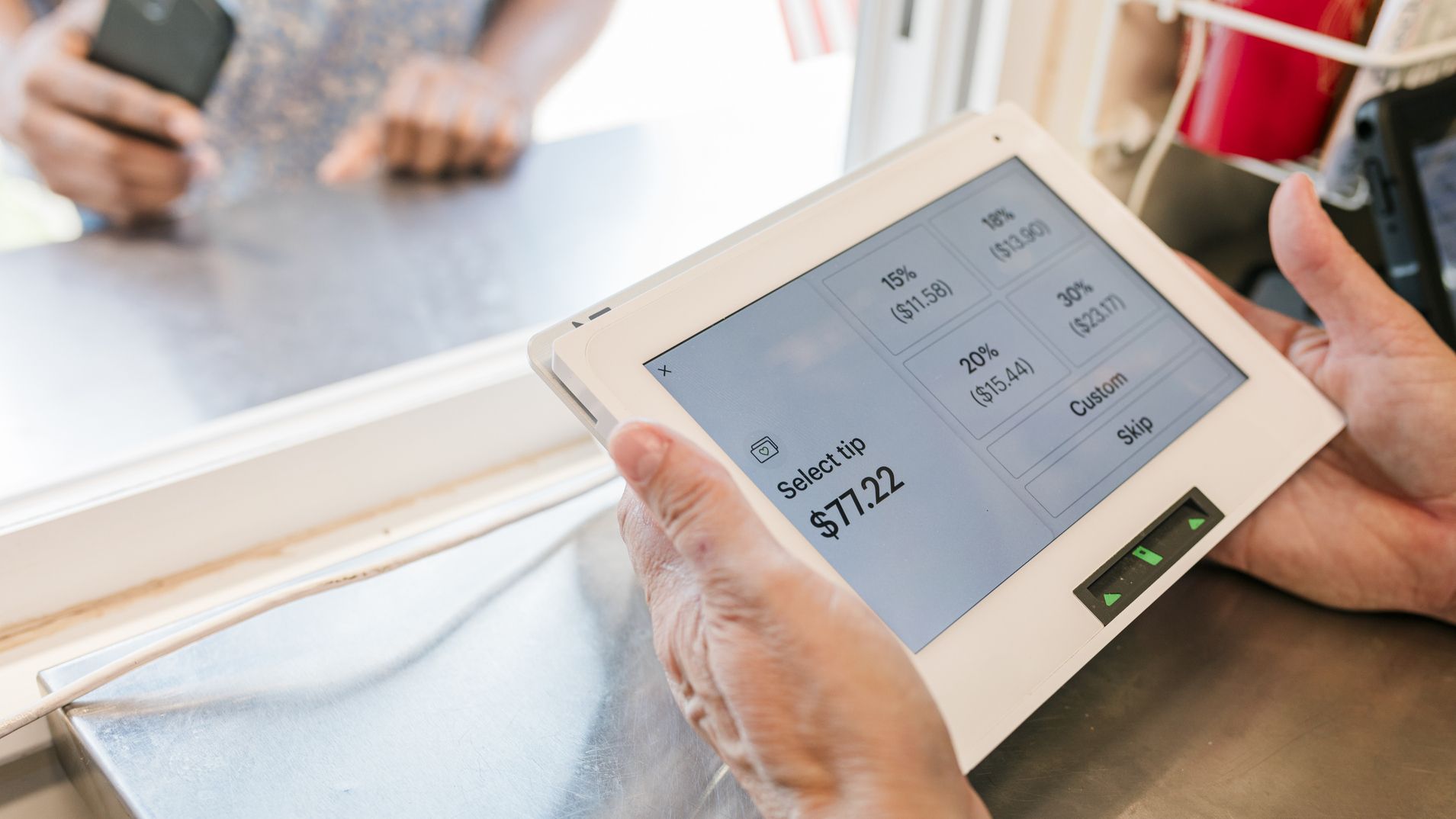 A food truck worker handing a customer the credit card processing tablet.