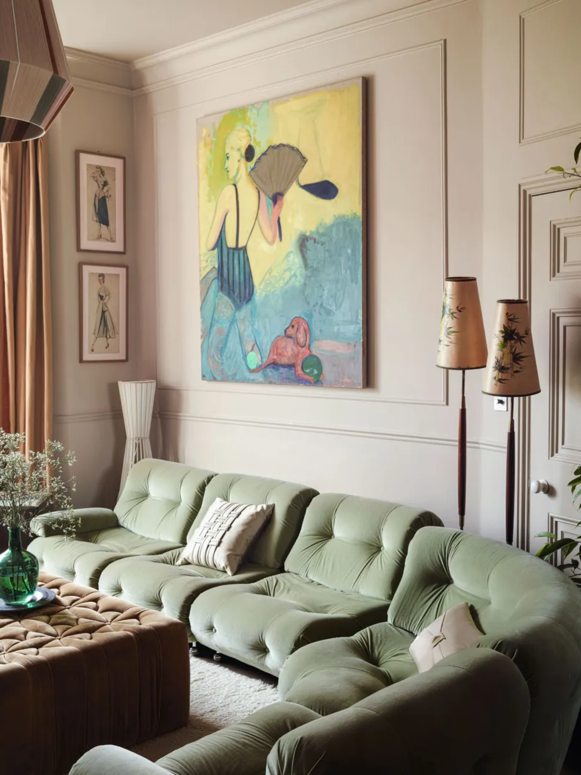 Pale pink panelled living room with velvet green sofa, large painting and velvet ottoman