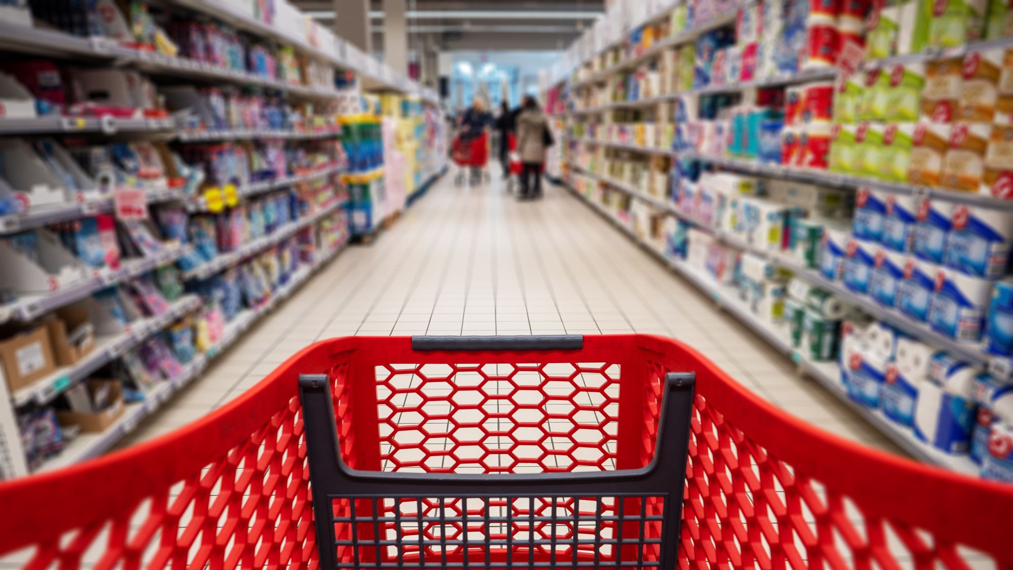 Personal perspective of a shopper pushing shopping cart along aisle while shopping in a supermarket.