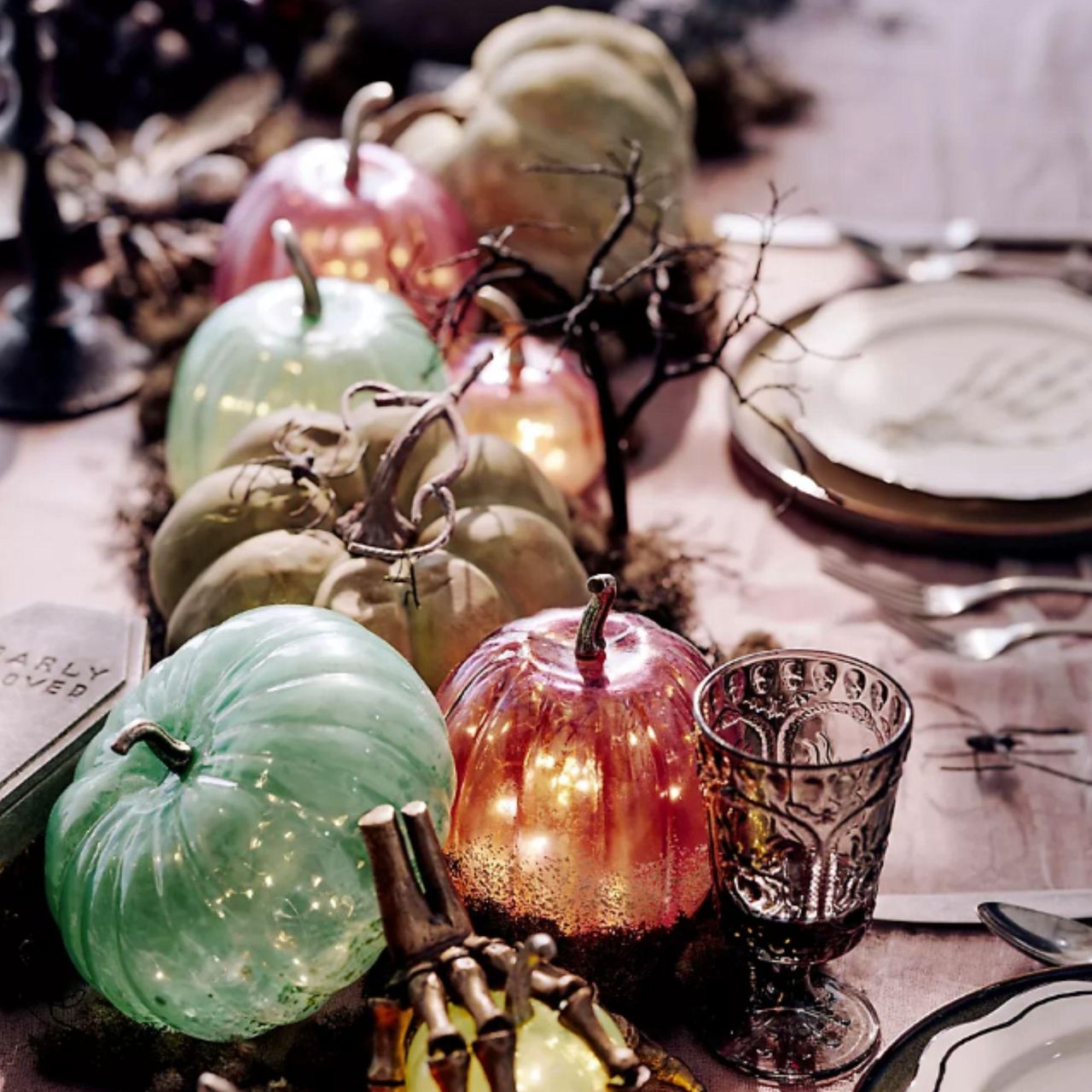 Halloween tablescape with glass pumpkins and a skeleton hand