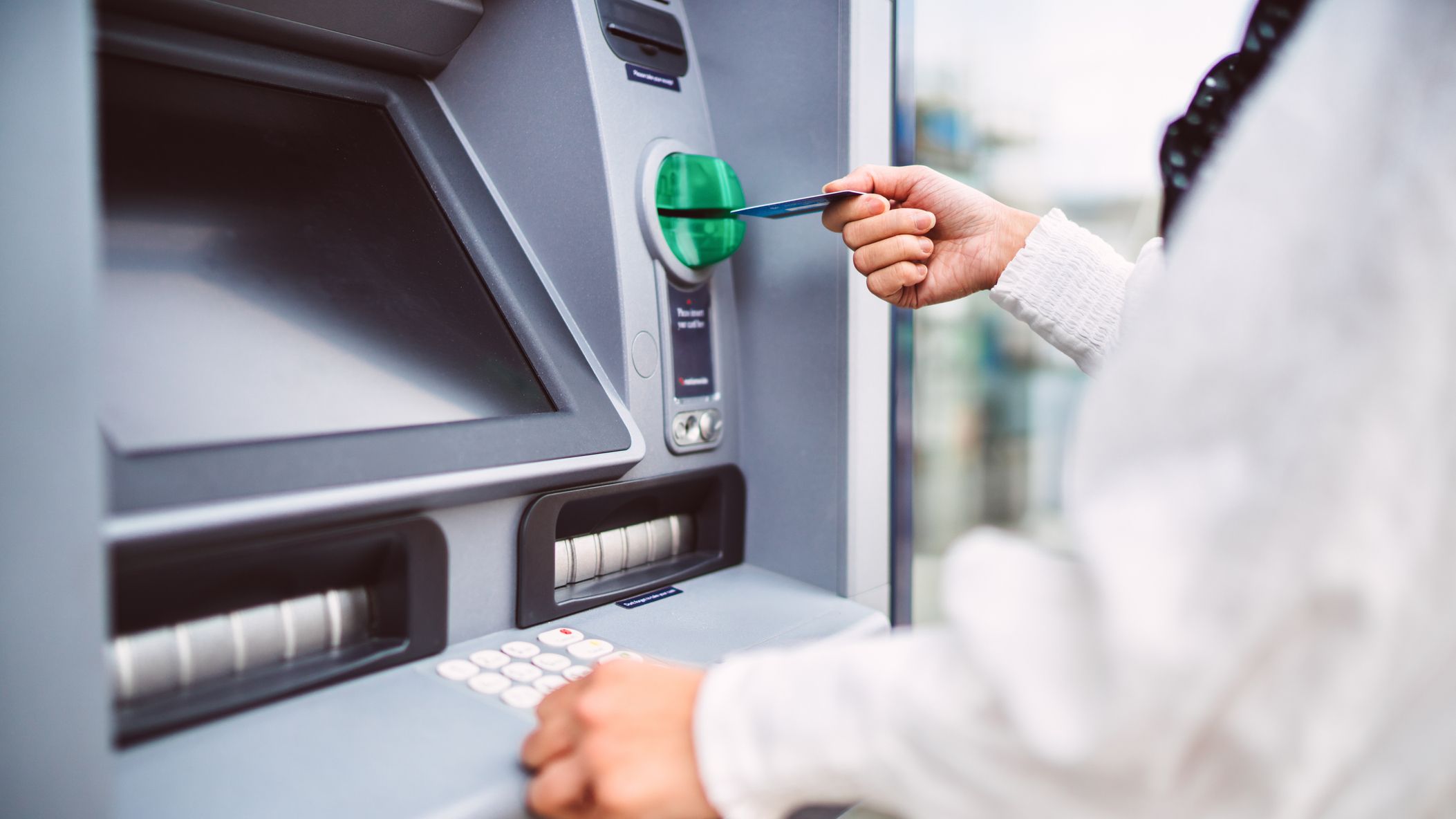 Woman inserting bank card into ATM machine