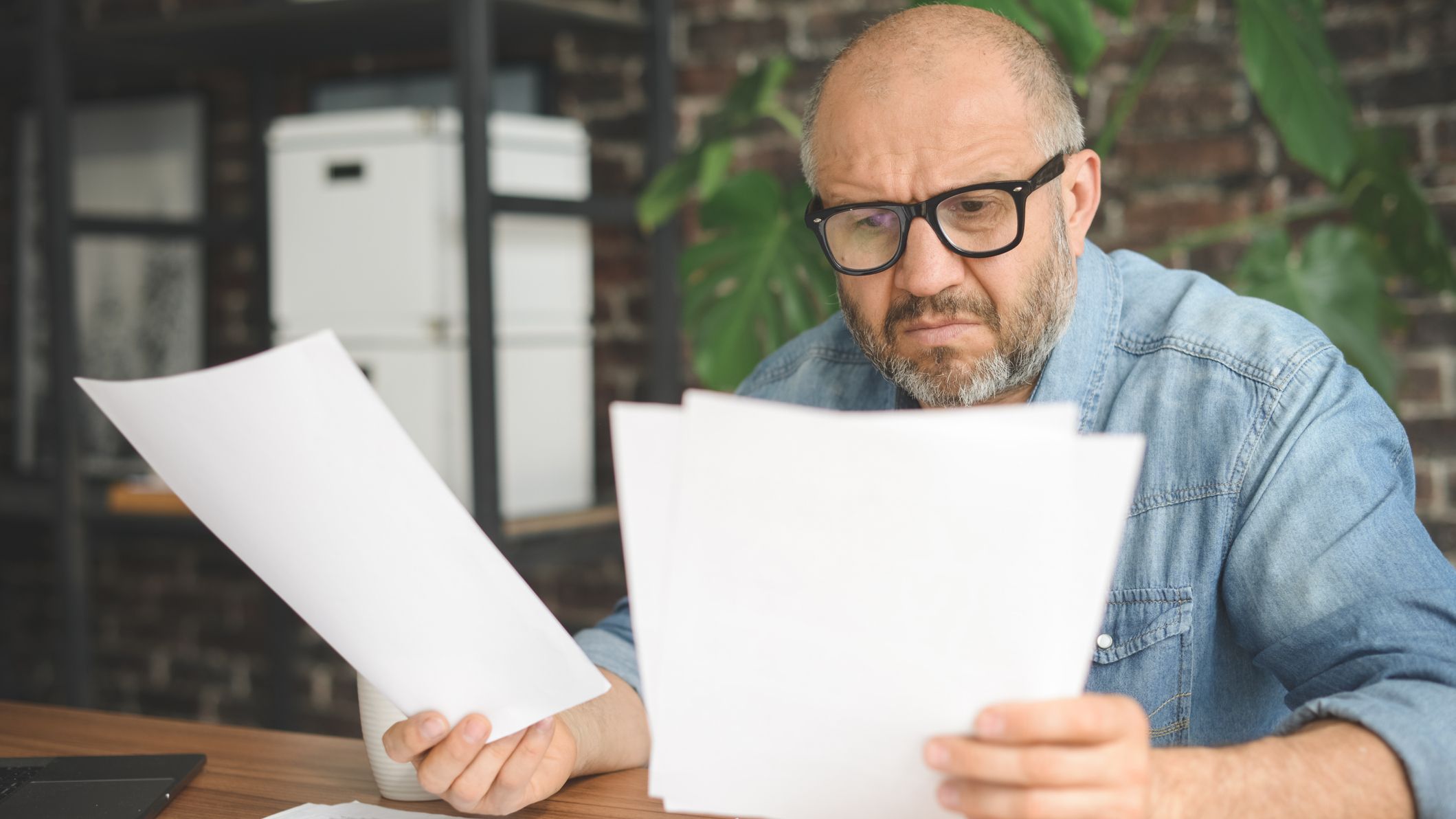 A man sorting through paperwork at a desk.