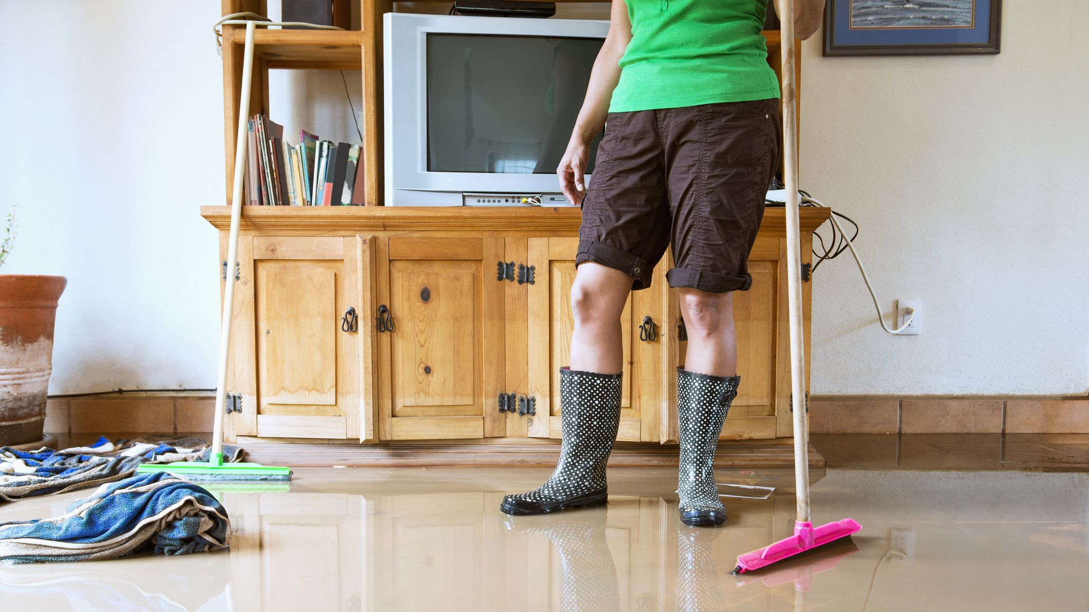A woman cleaning up flood water in a living room.