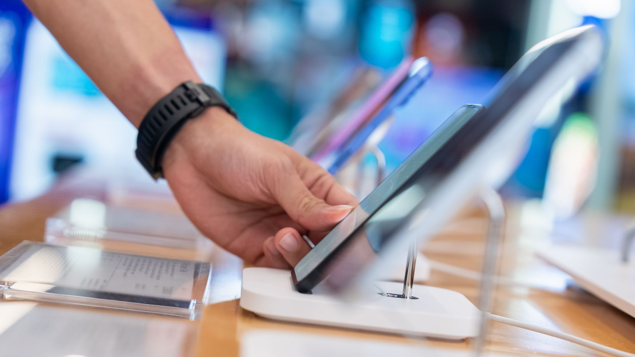 A hand reaching for a cell phone on display