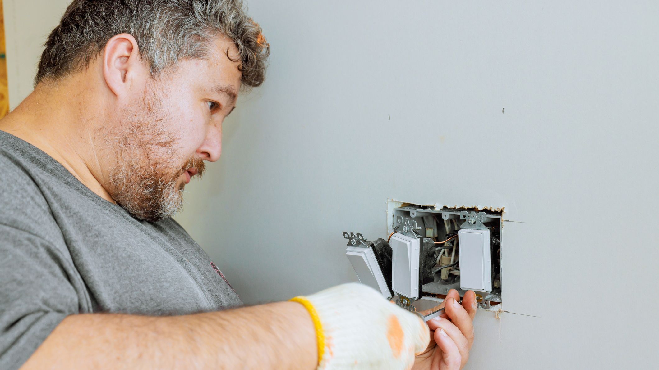 Electrician working on wall outlets during home renovation project in daylight