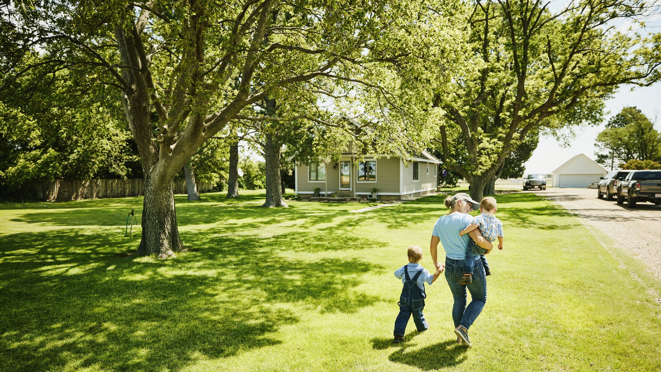 A mother with two kids walks across the lawn of a Kansas home.