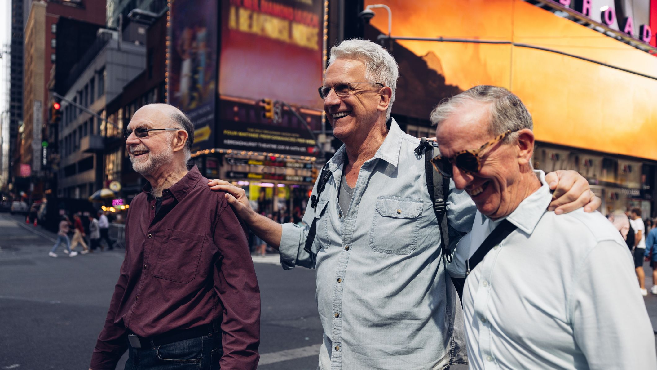 Three mature friends looking around Times Square in New York. They walk in the crowded city street in Manhattan