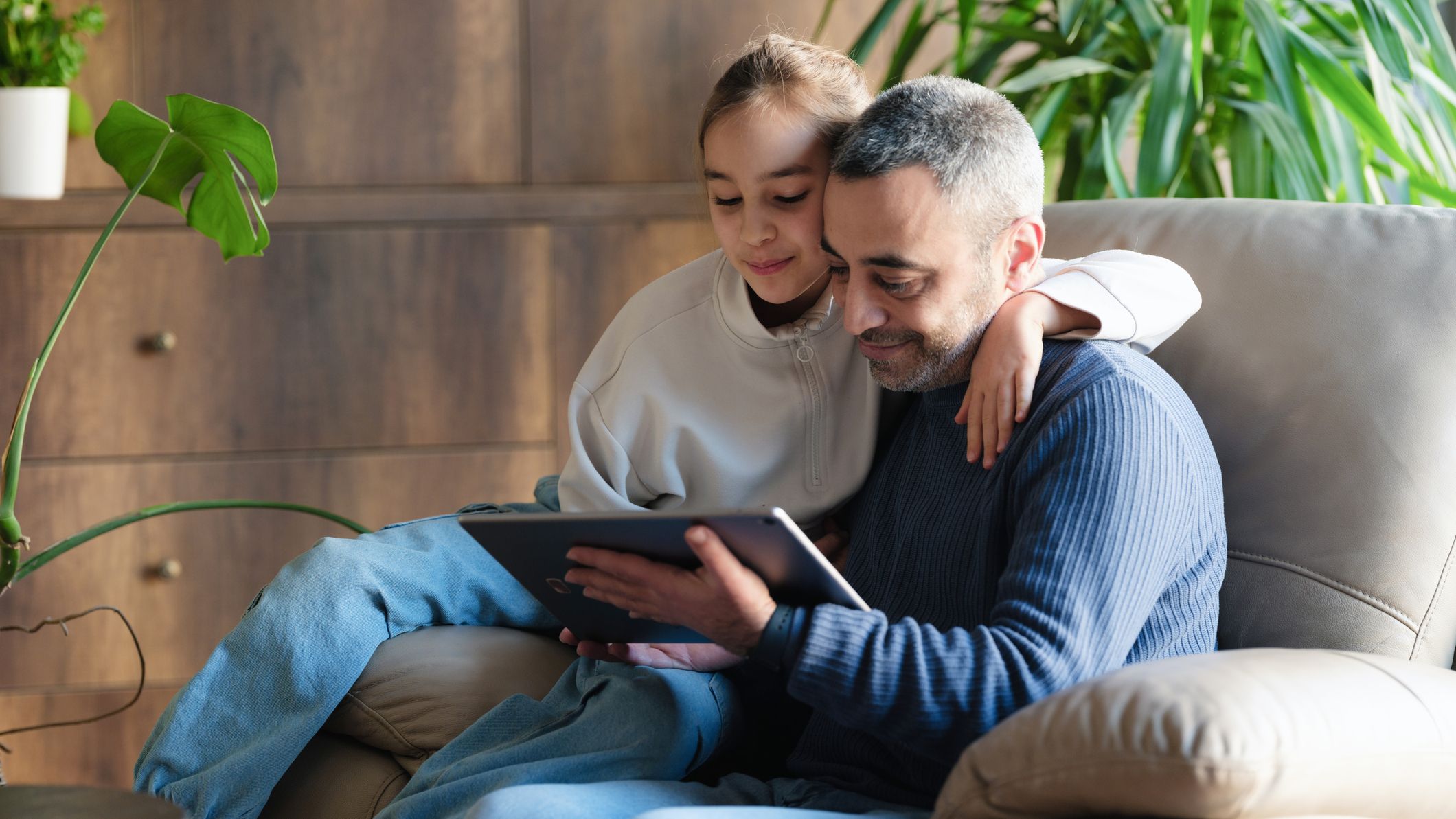 Father and child daughter trying a mobile application using digital tablet at home