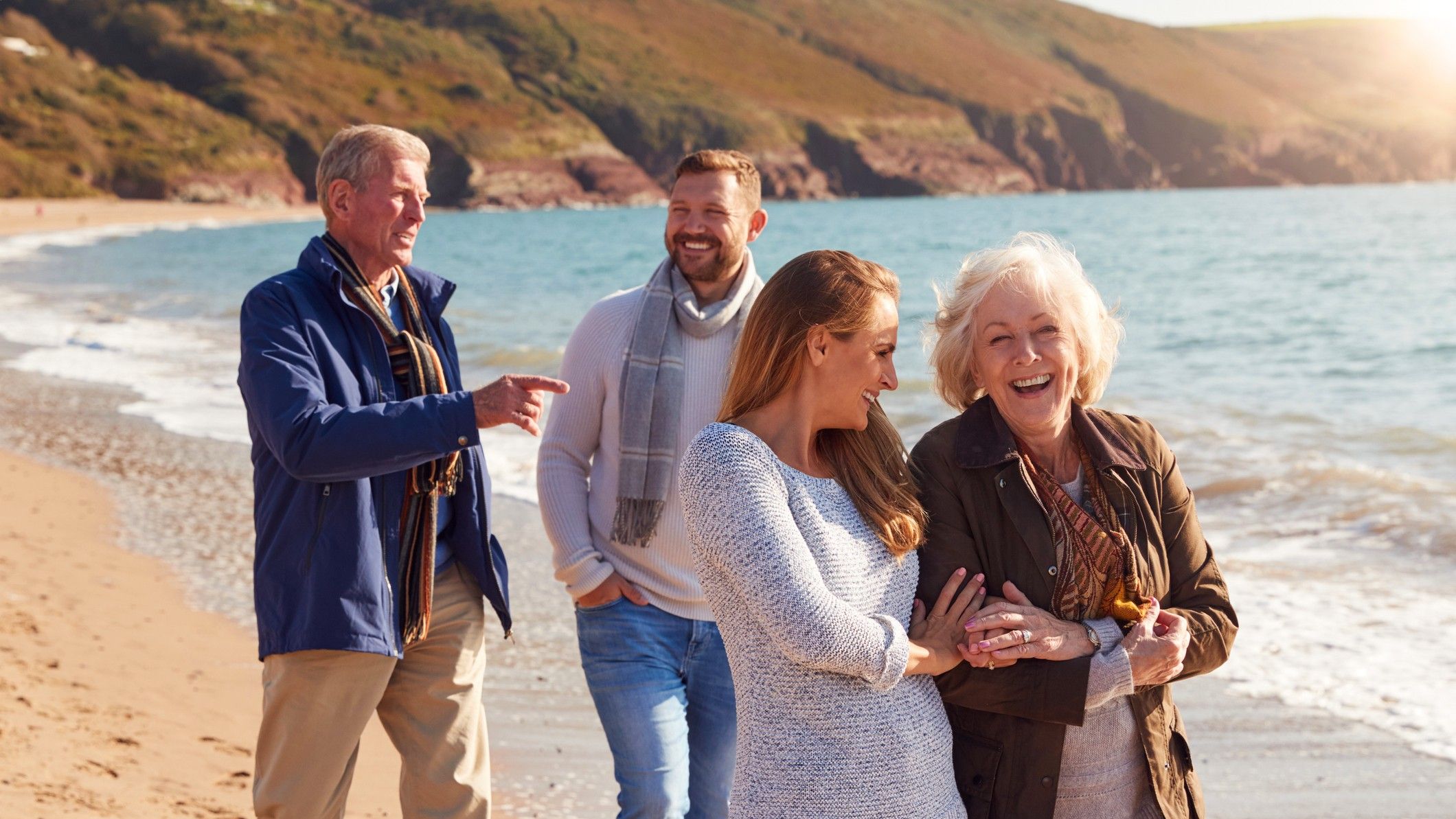 Senior Couple Walking Along Shoreline With Adult Offspring On a Winter Beach Vacation.