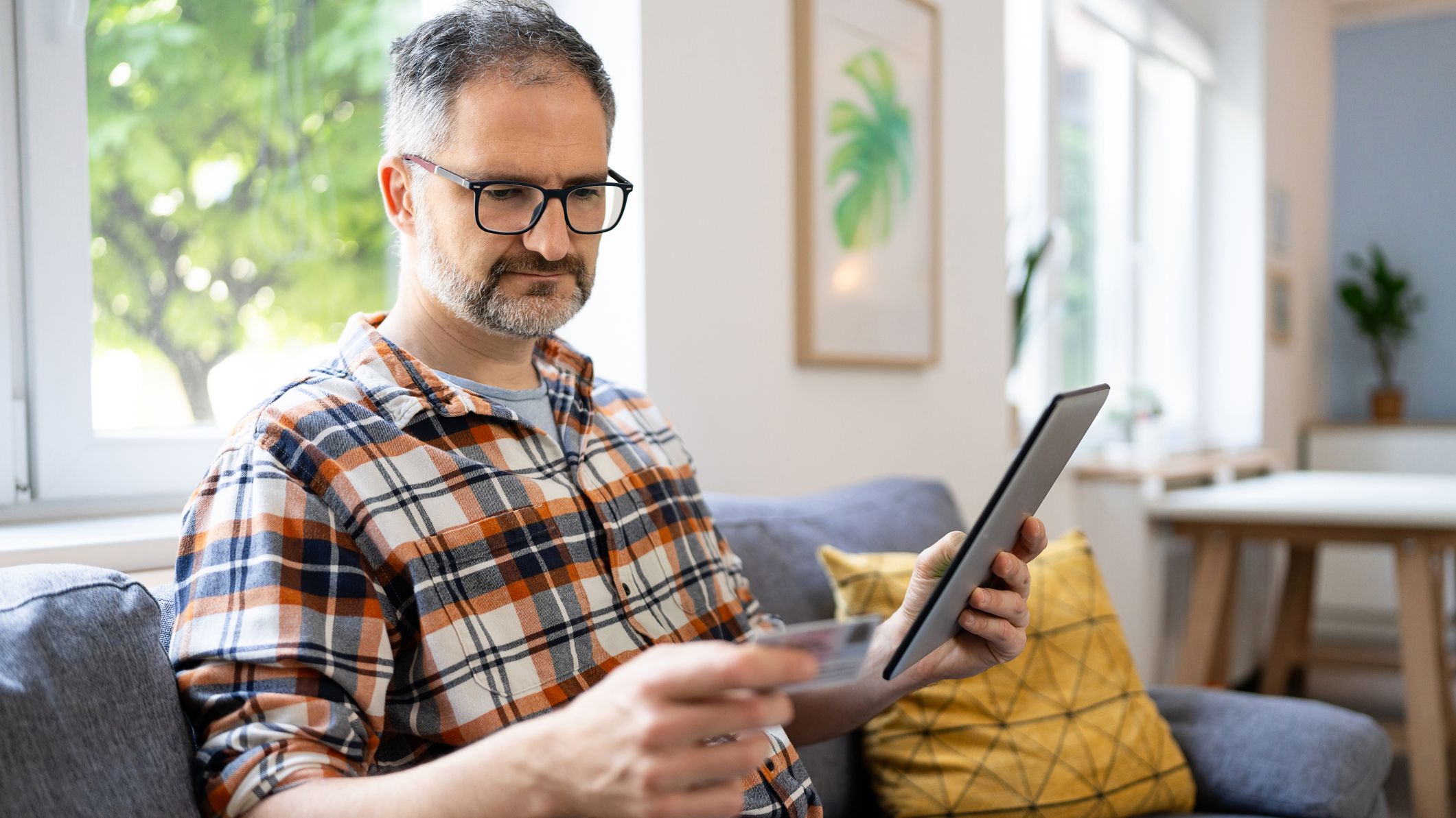 Man typing his social security number over a digital tablet from home.