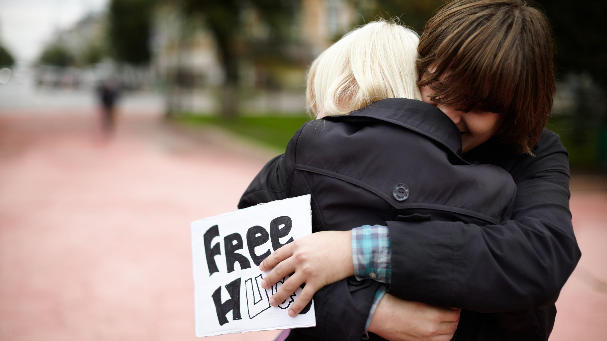 Samara, Russia - September 25, 2011: A young man hugs a blonde woman on the street, holding a sign offering "free hugs" to anyone on a gloomy and rainy autumn day.