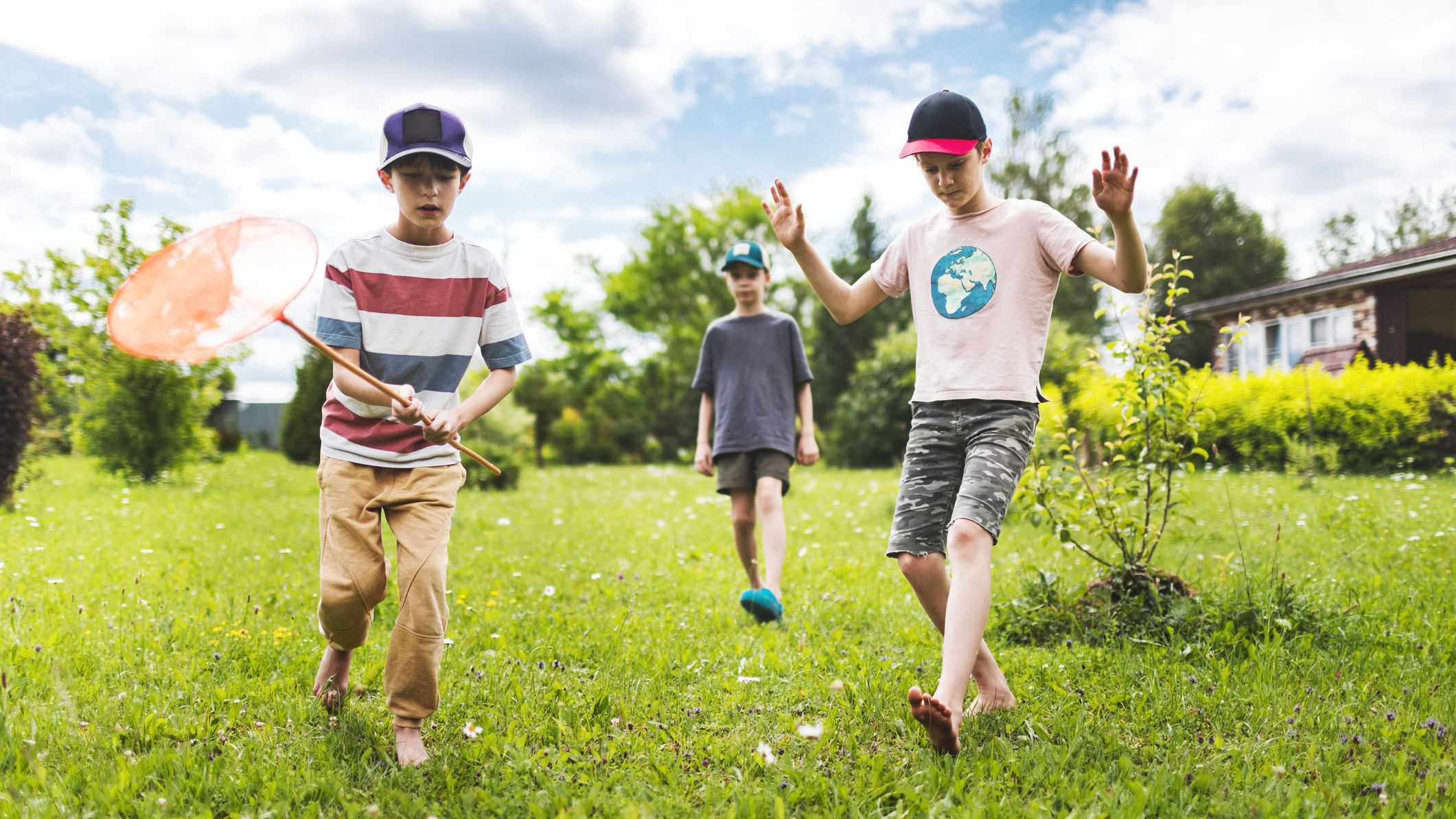 Three boys catching bugs in the backyard