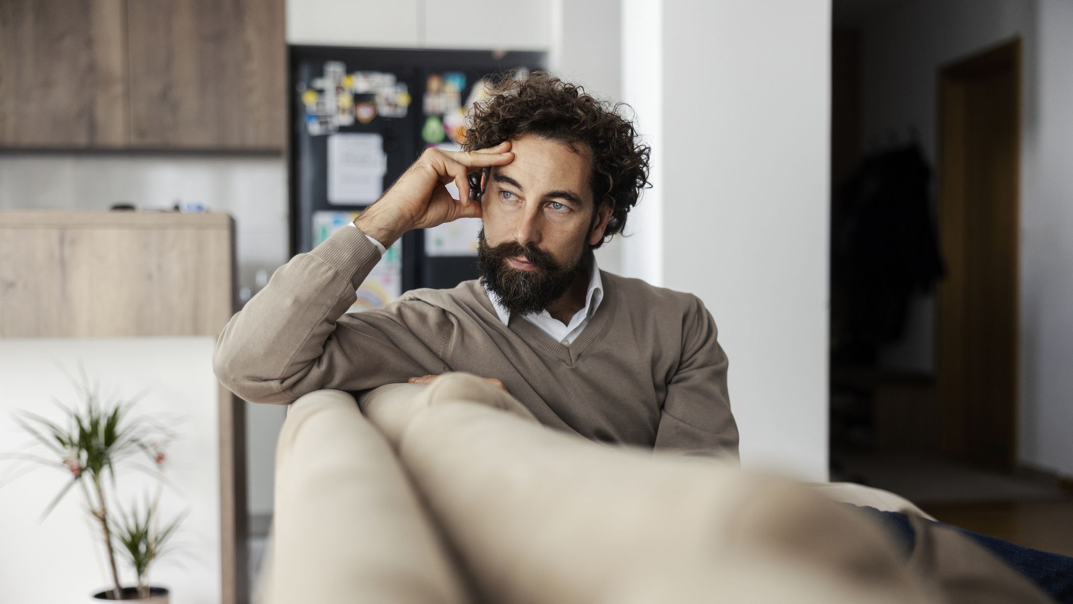 Man thinking on couch at home, deep in contemplation
