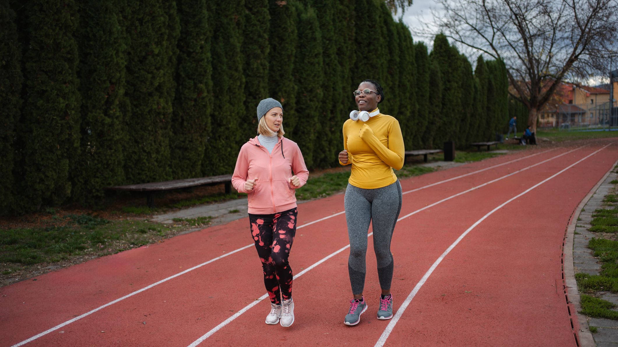 Two women running outdoors on a track, enjoying exercise and conversation