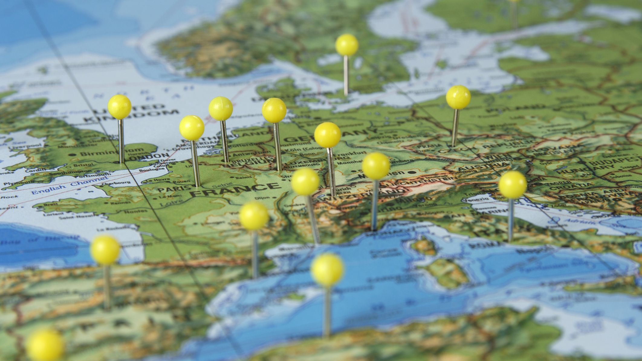 Paper map showing different countries in Europe including France and Germany with yellow push pins