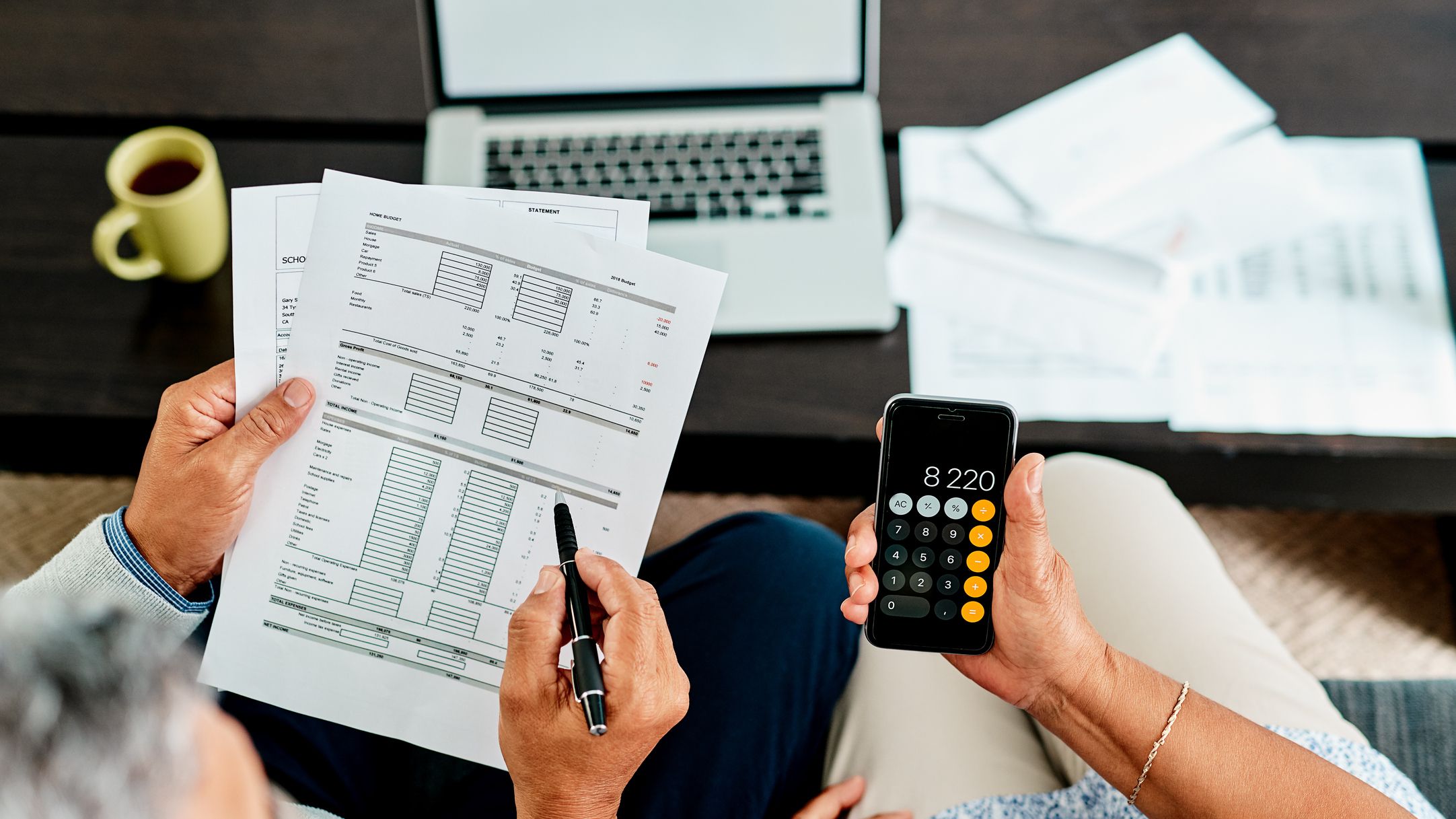 A senior couple evaluates their finances with a calculator.