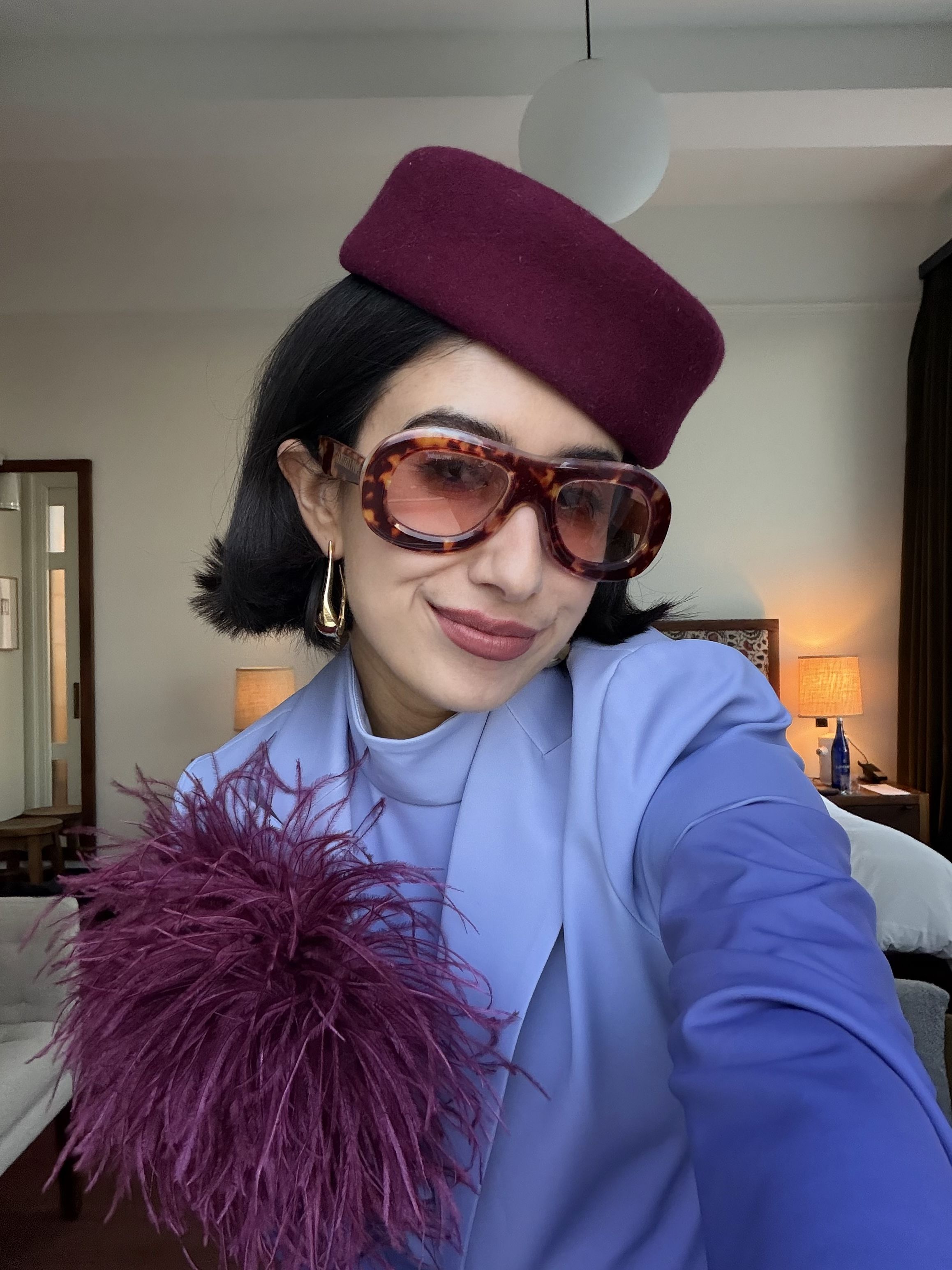 April Lockhart matches her plum toque to her oversized feather brooch