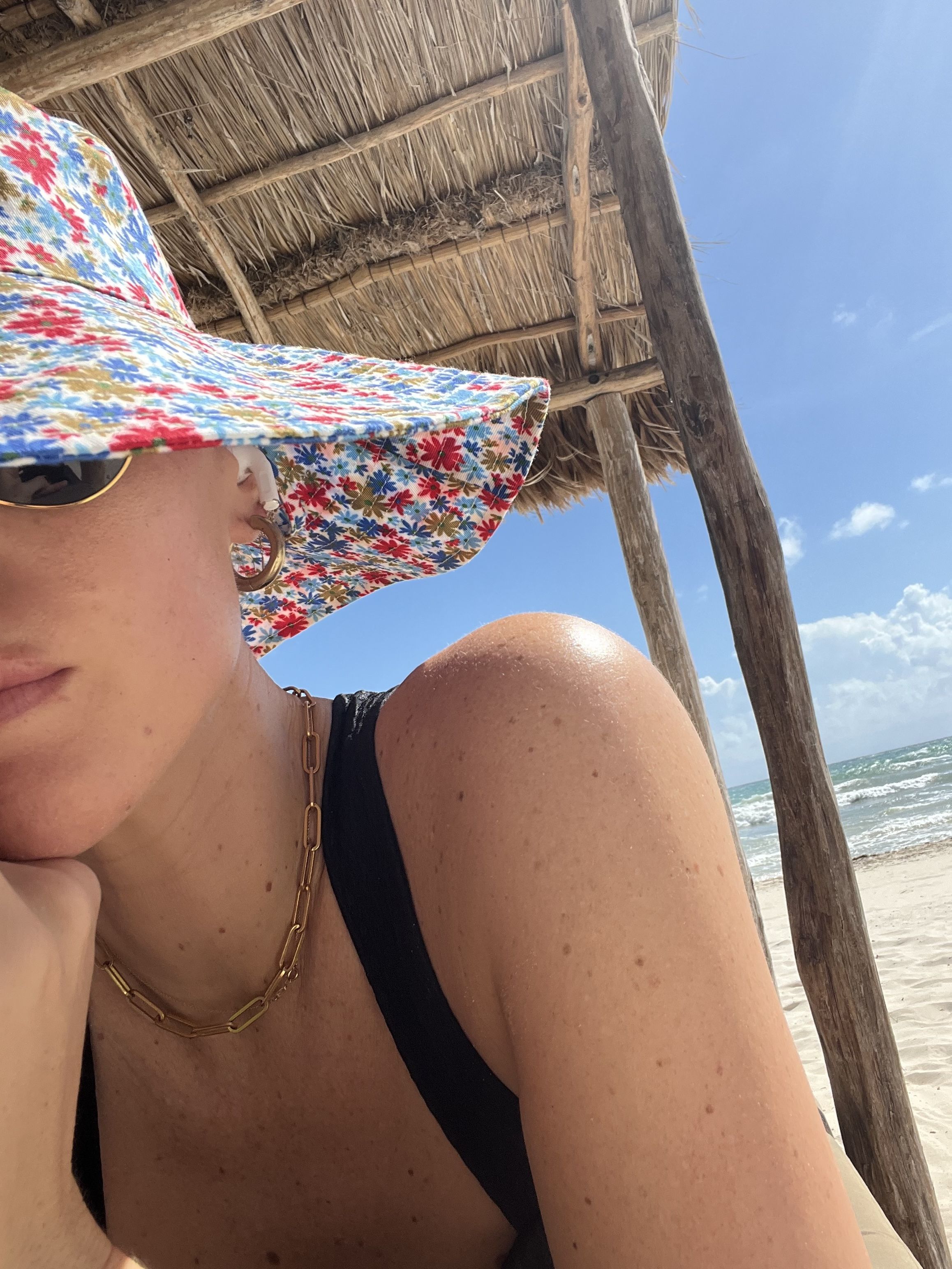 Brooke Ely Danielson wears a colorful floral sunhat on the beach