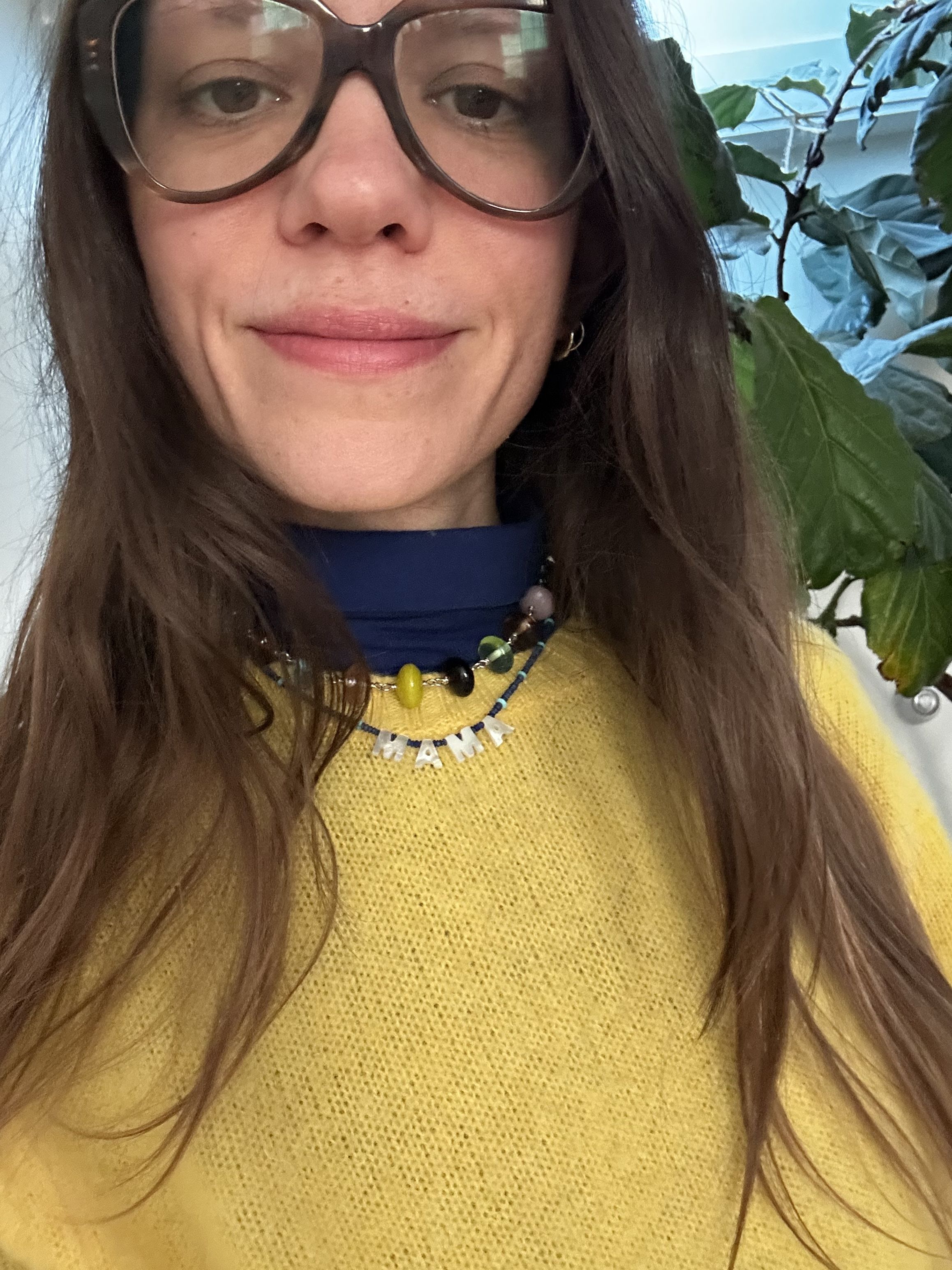 Julia Gall styles a big beaded necklace over a "mama" necklace and yellow sweater