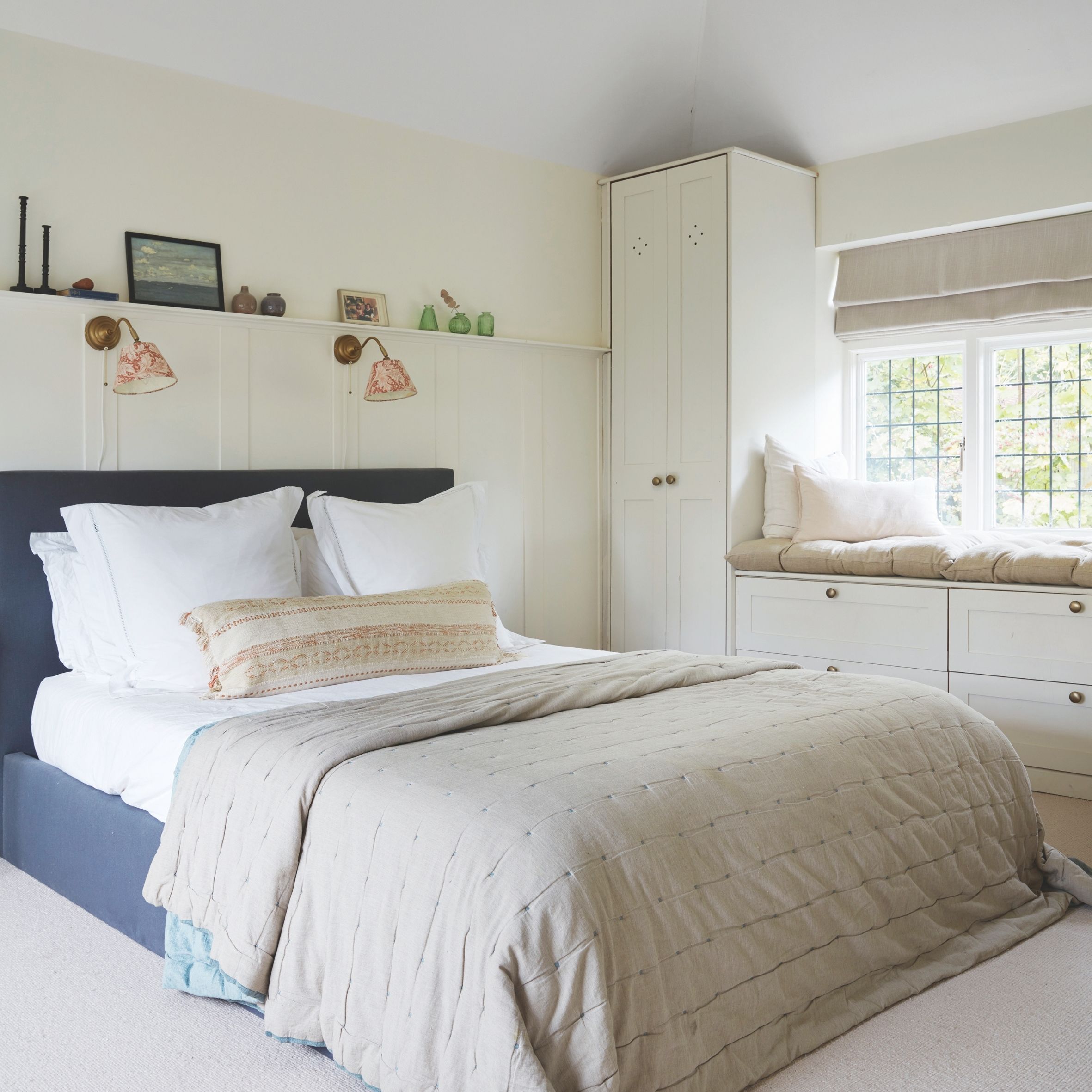 White bedroom with built-in furniture, navy bed and wall lights