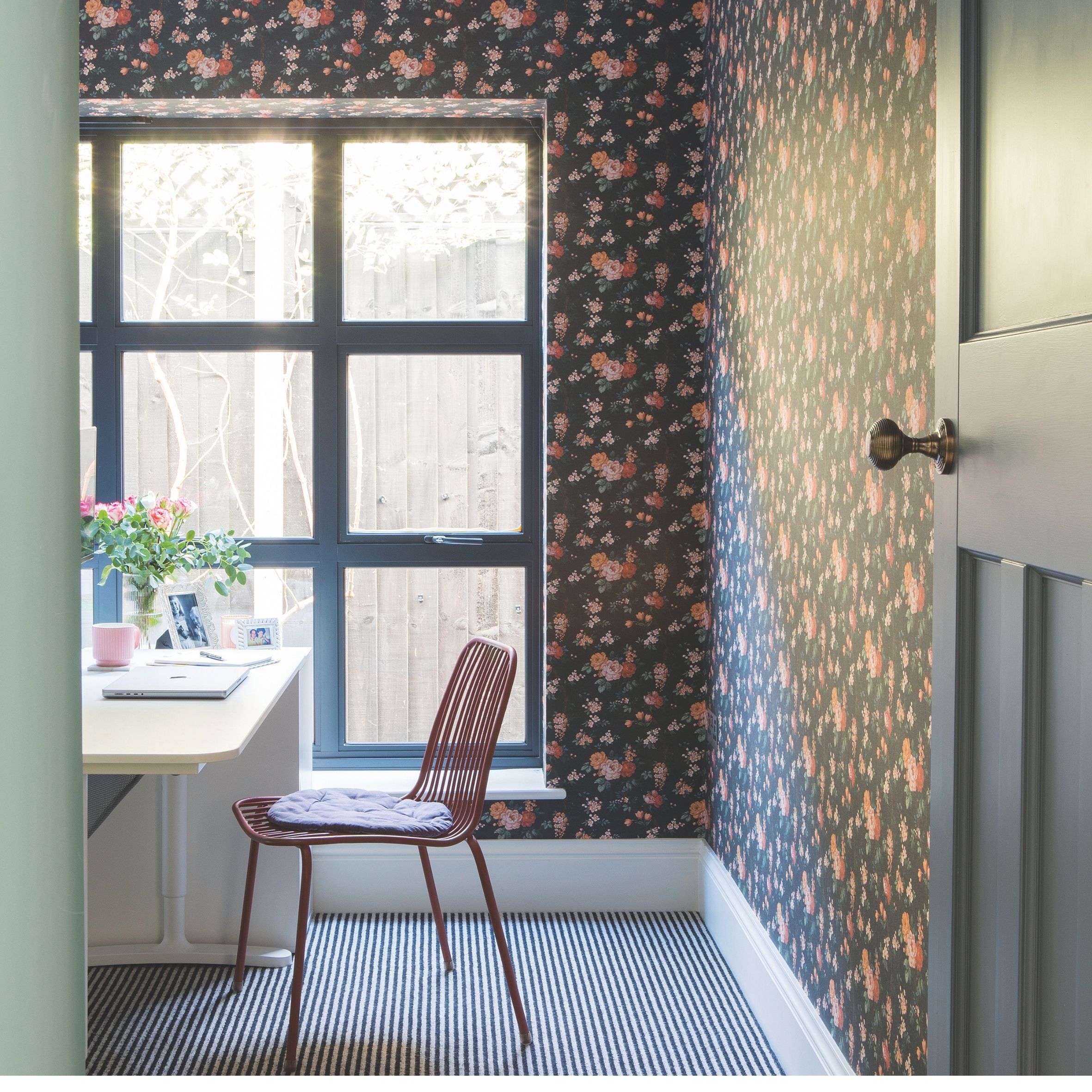 Study with striped carpet, floral wallpaper and large black windows