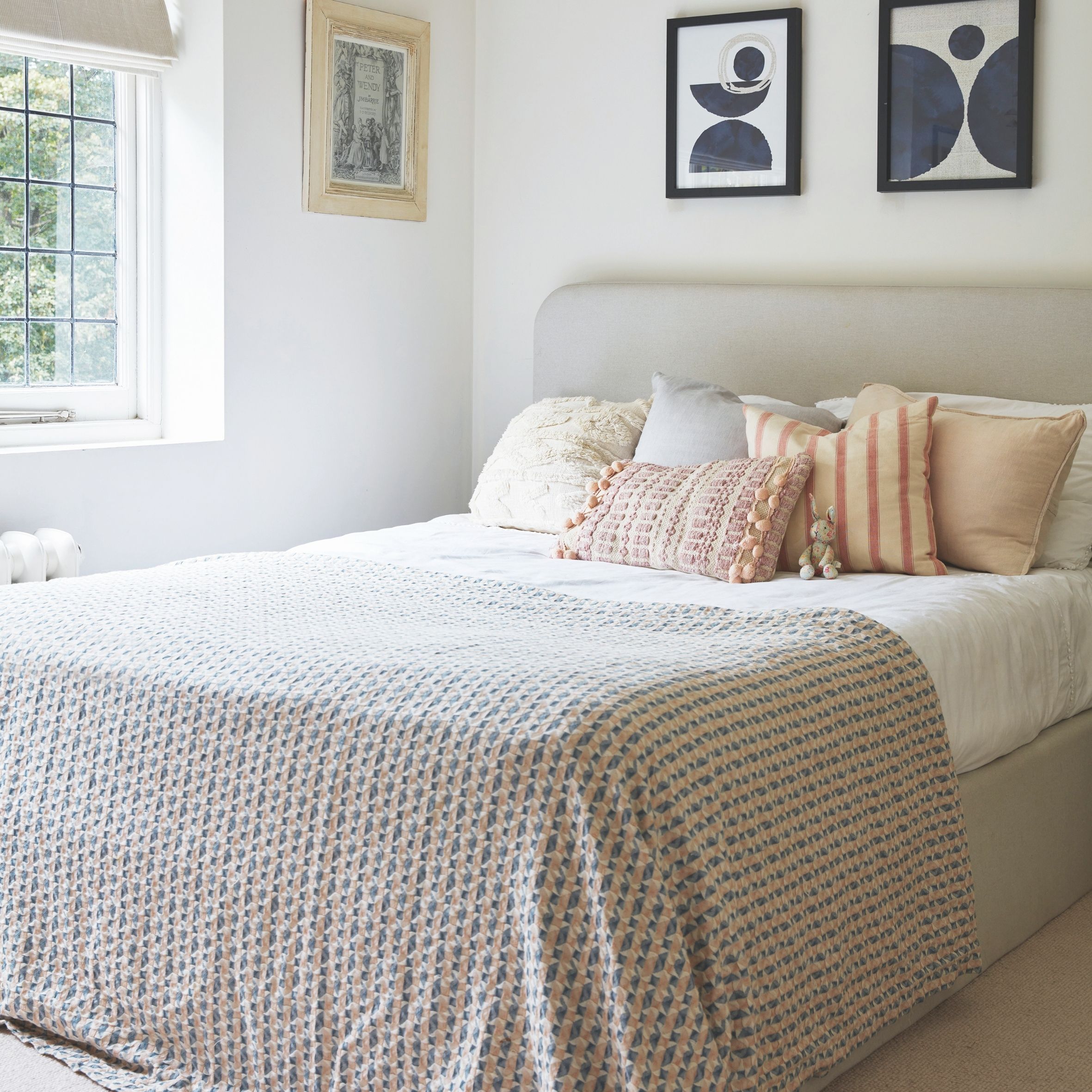 Neutral kids room with grey double bed and wall art