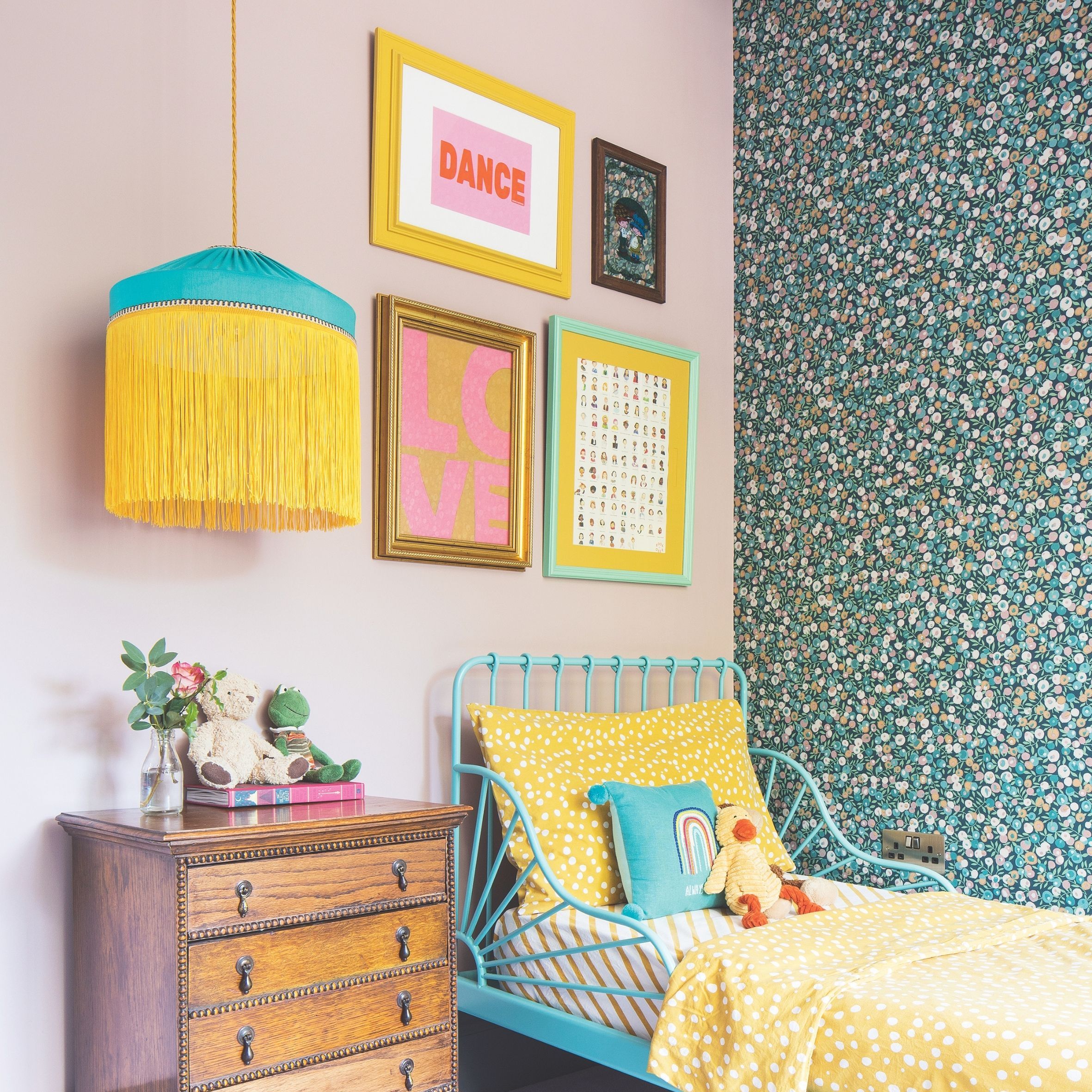 Colourful kids bedroom with pink wall, blue metal bed, floral wallpaper and wooden bedside table