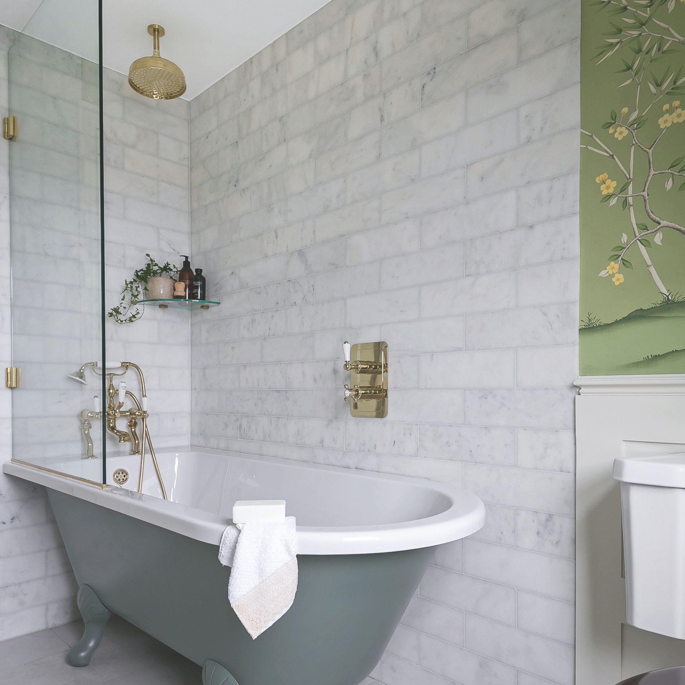 White marble walls, gold accents and freestanding tub with grey colour