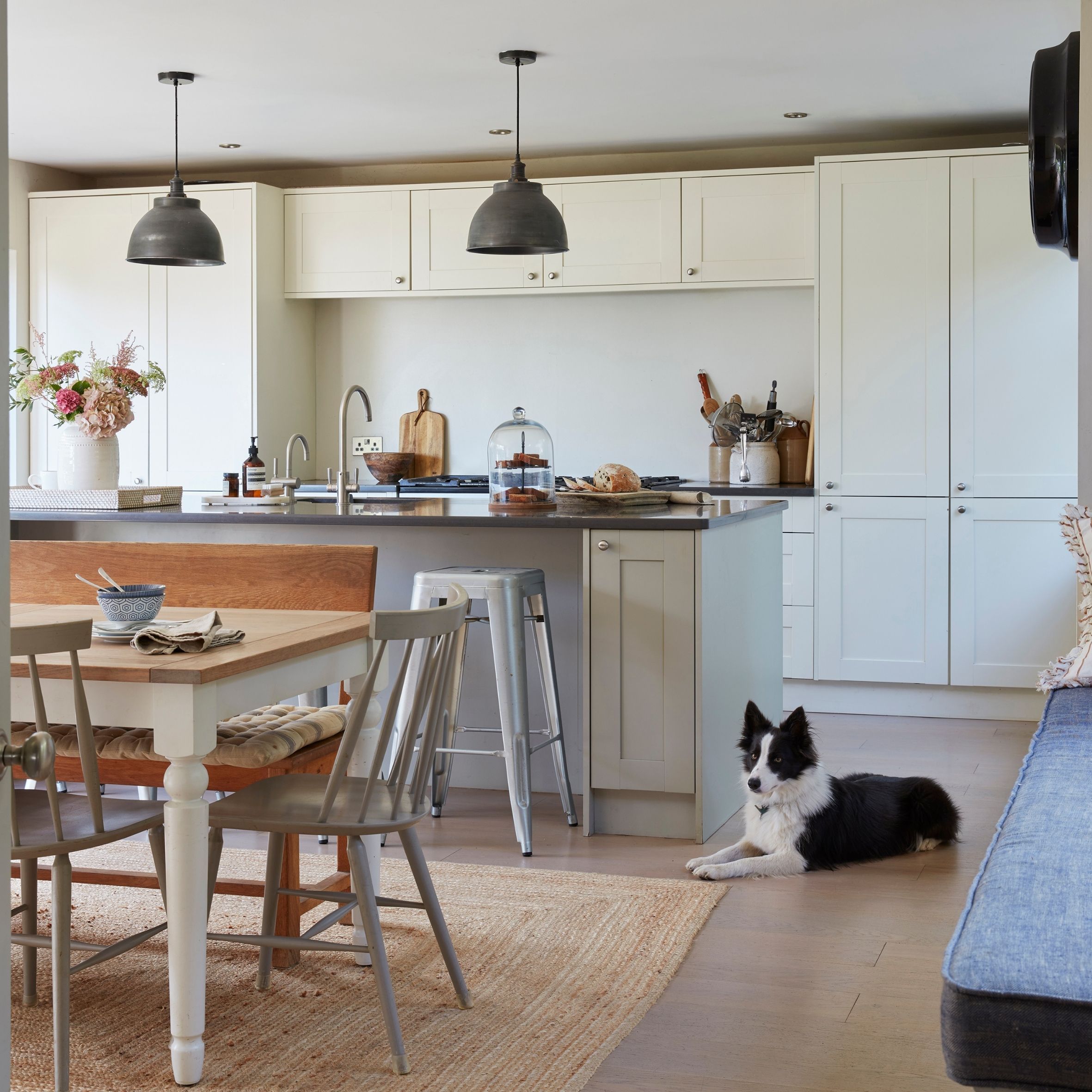 Kitchen with shaker style cabinets, wooden table and large jute rug with dog