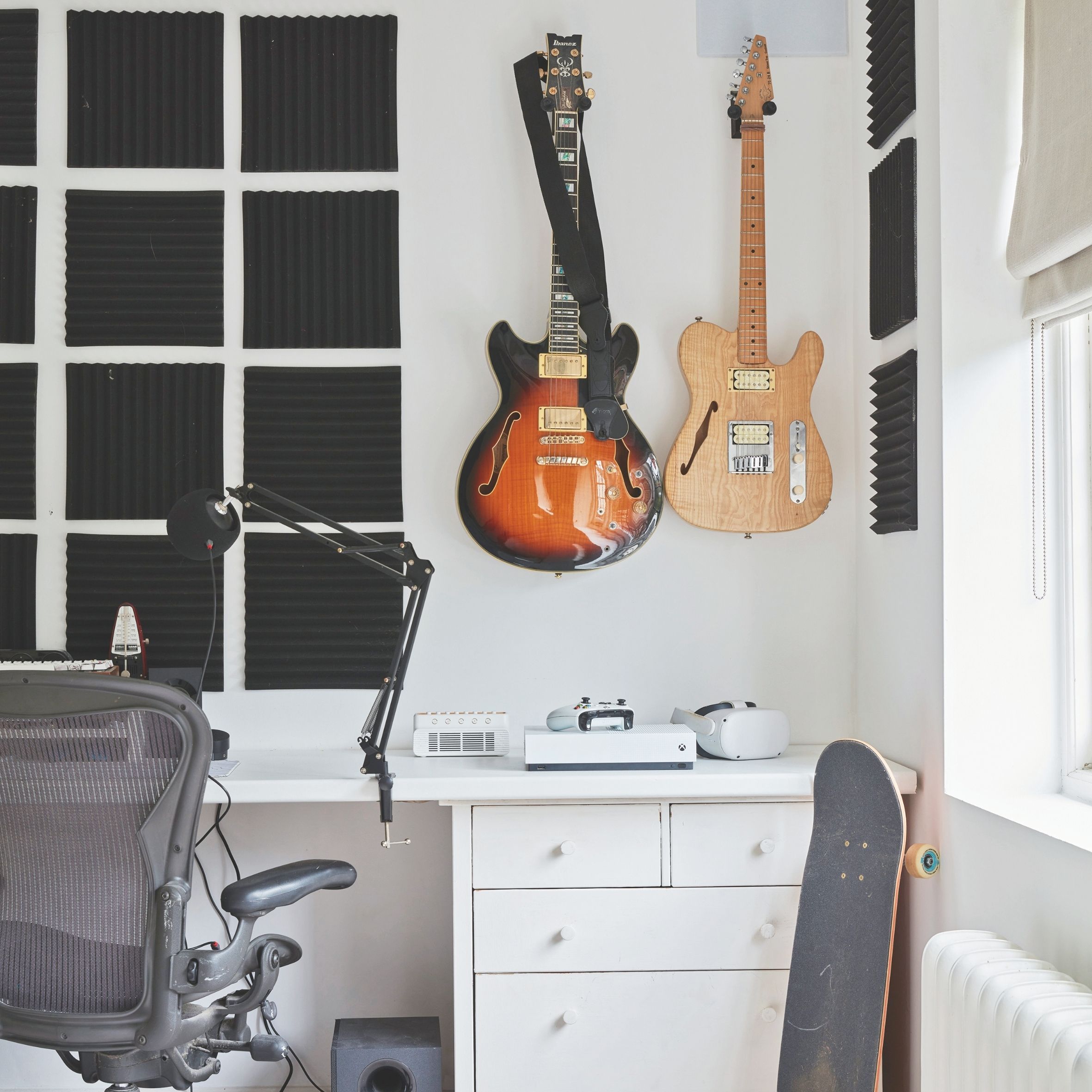 Teenagers room with white desk and chest, guitar on the wall and skateboard