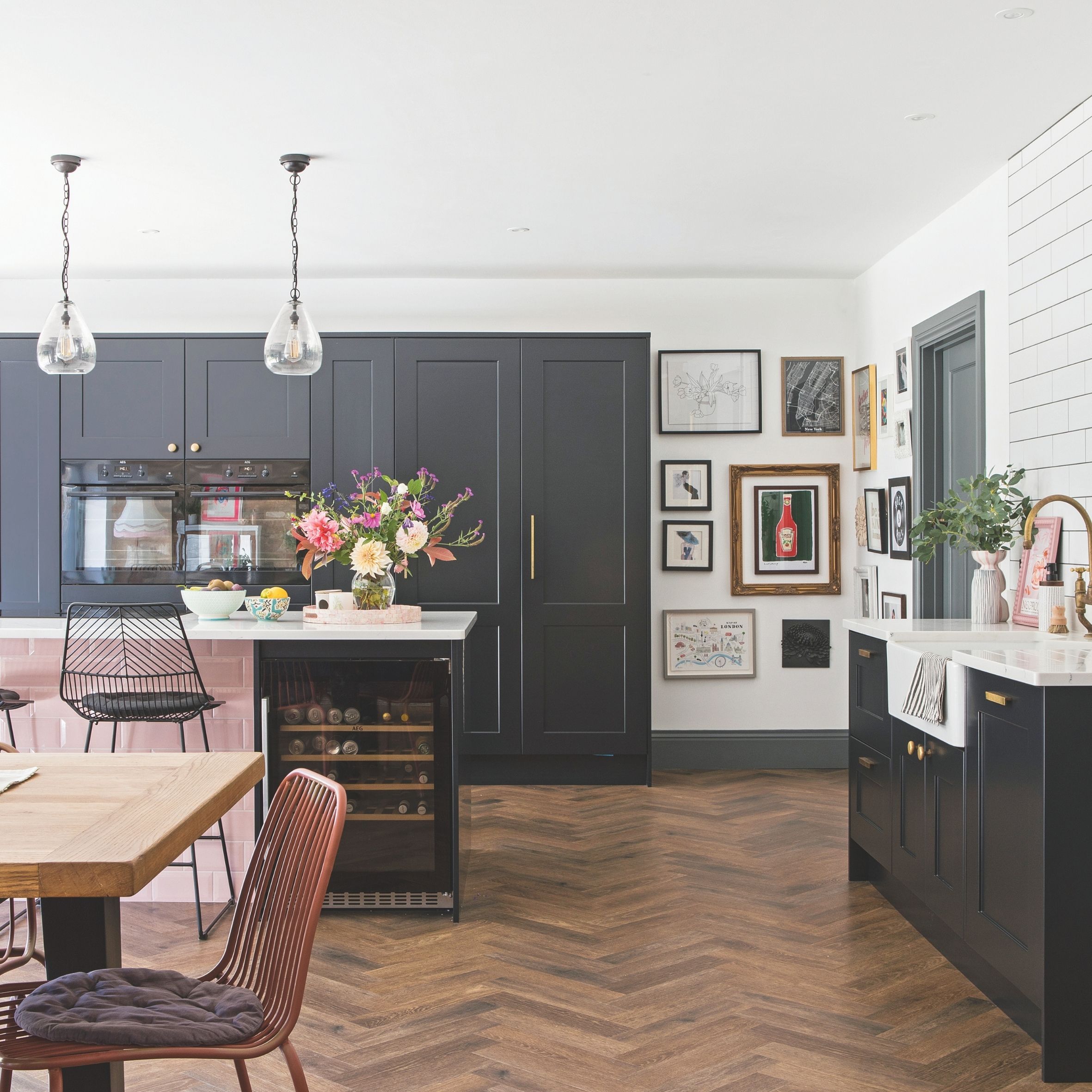 Kitchen diner open plan with navy cabinetry, pink tiles, gallery wall and wooden floors