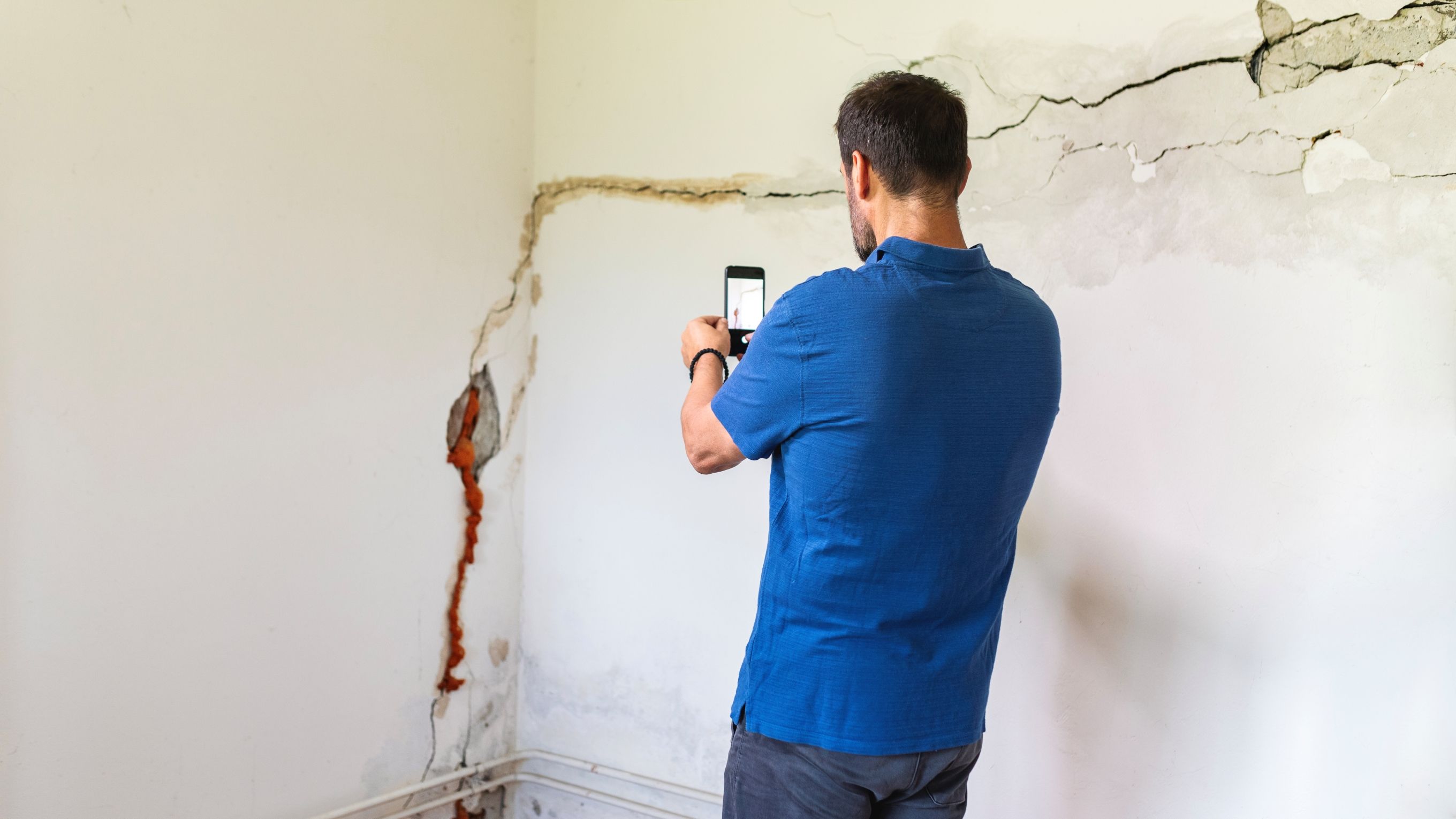 Mature man looking at a damaged wall