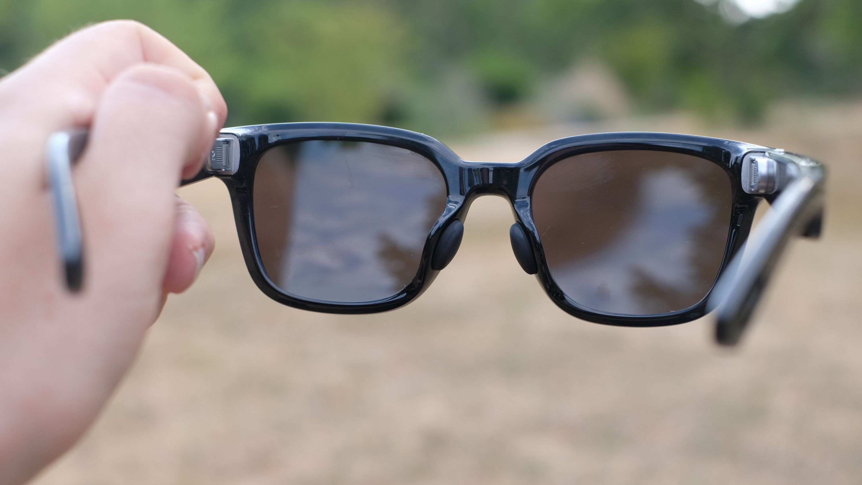 Hands-on photograph of Rokid AI Glasses Style held in man's hand facing away from camera