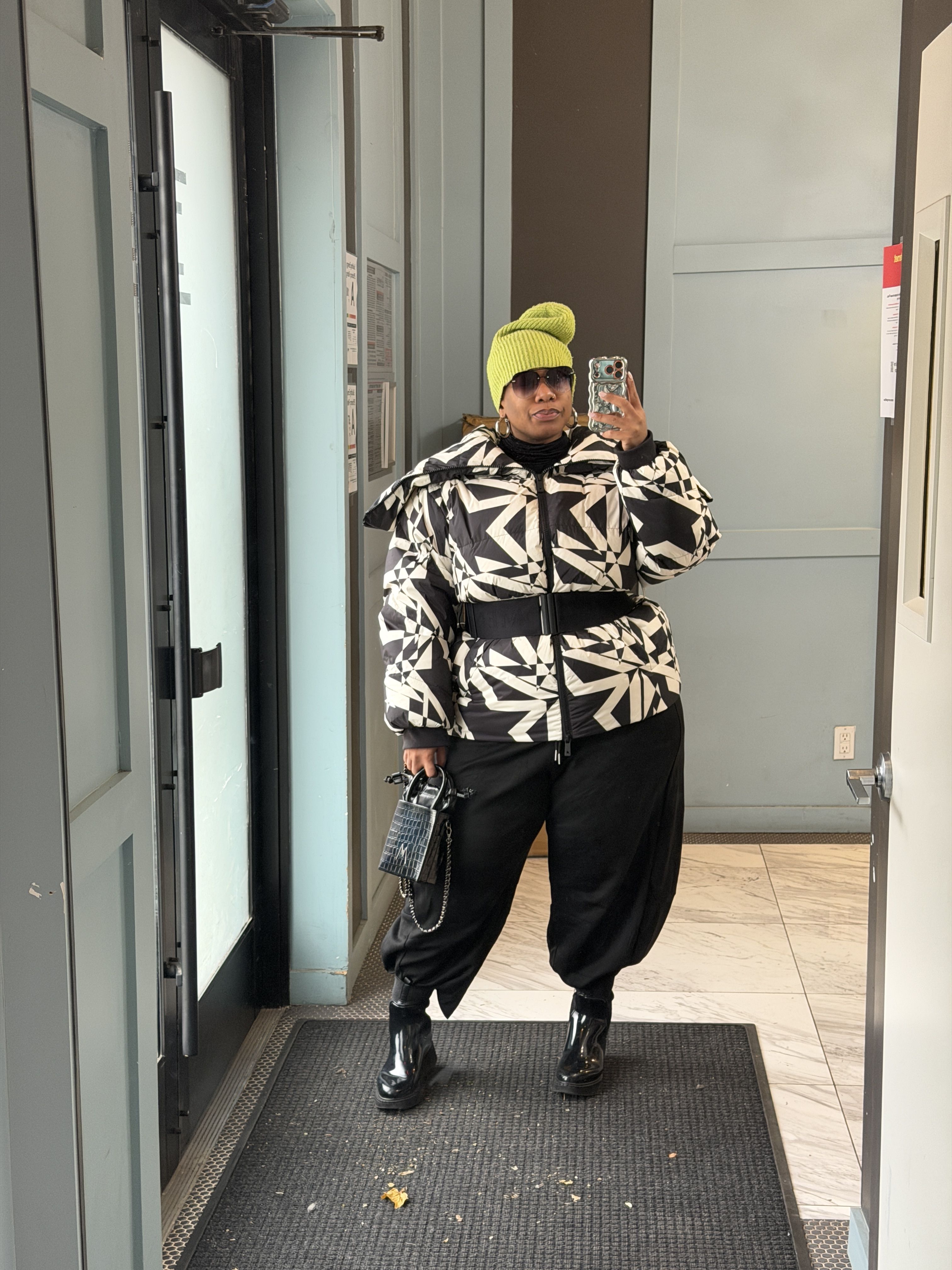 Kelly Augustine wearing a printed jacket, black trousers, and a lime green hat