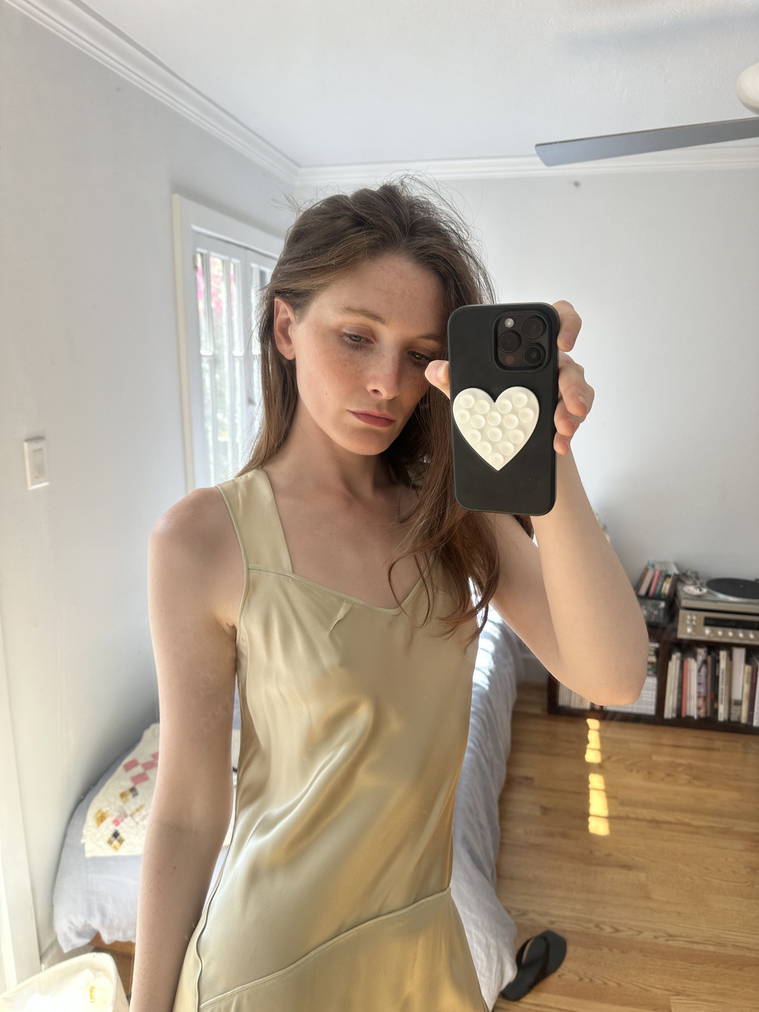 Grace O'Neill Dougherty takes a mirror selfie in a light colored satin dress