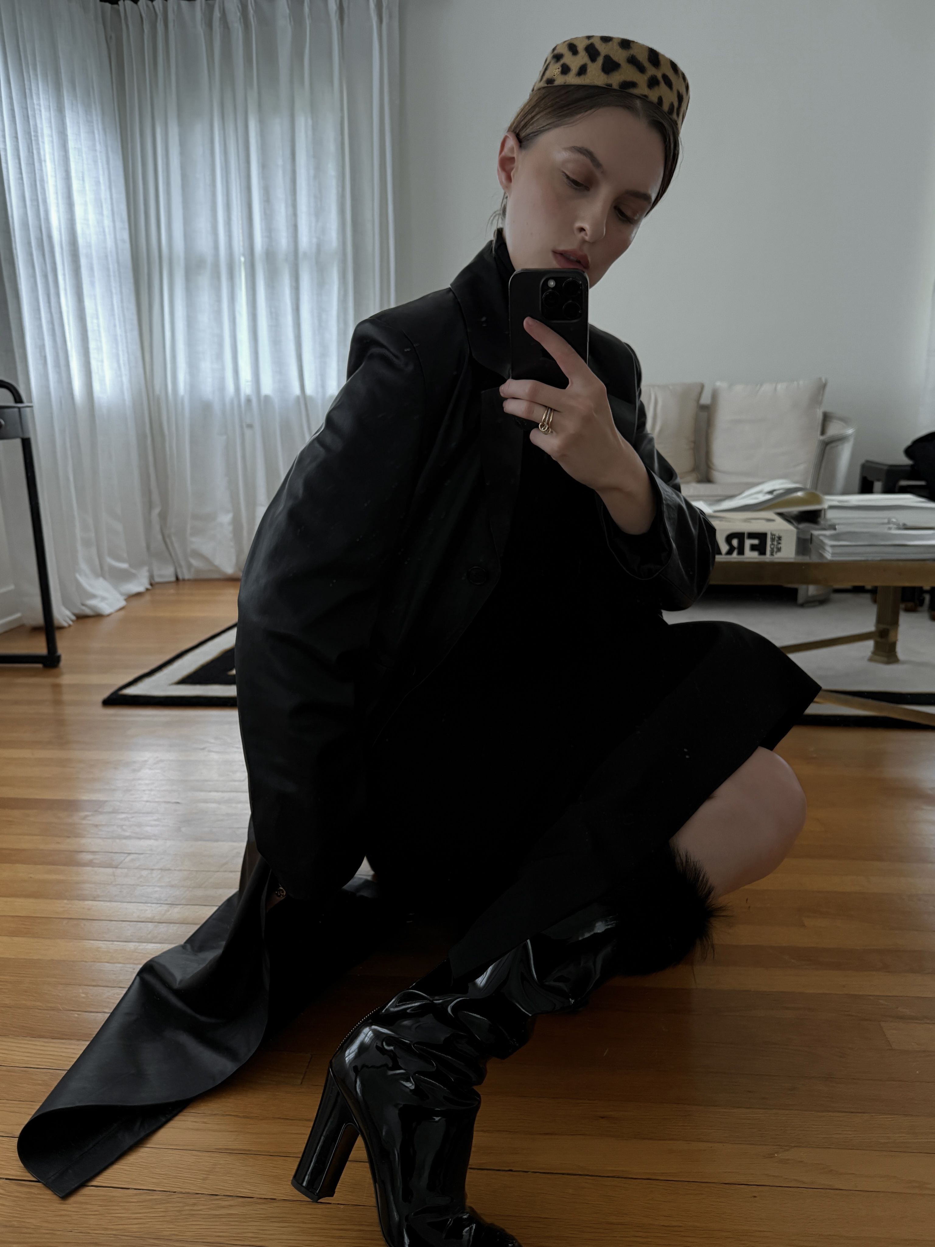 Christie Tyler sitting on the floor in a black dress and black boots