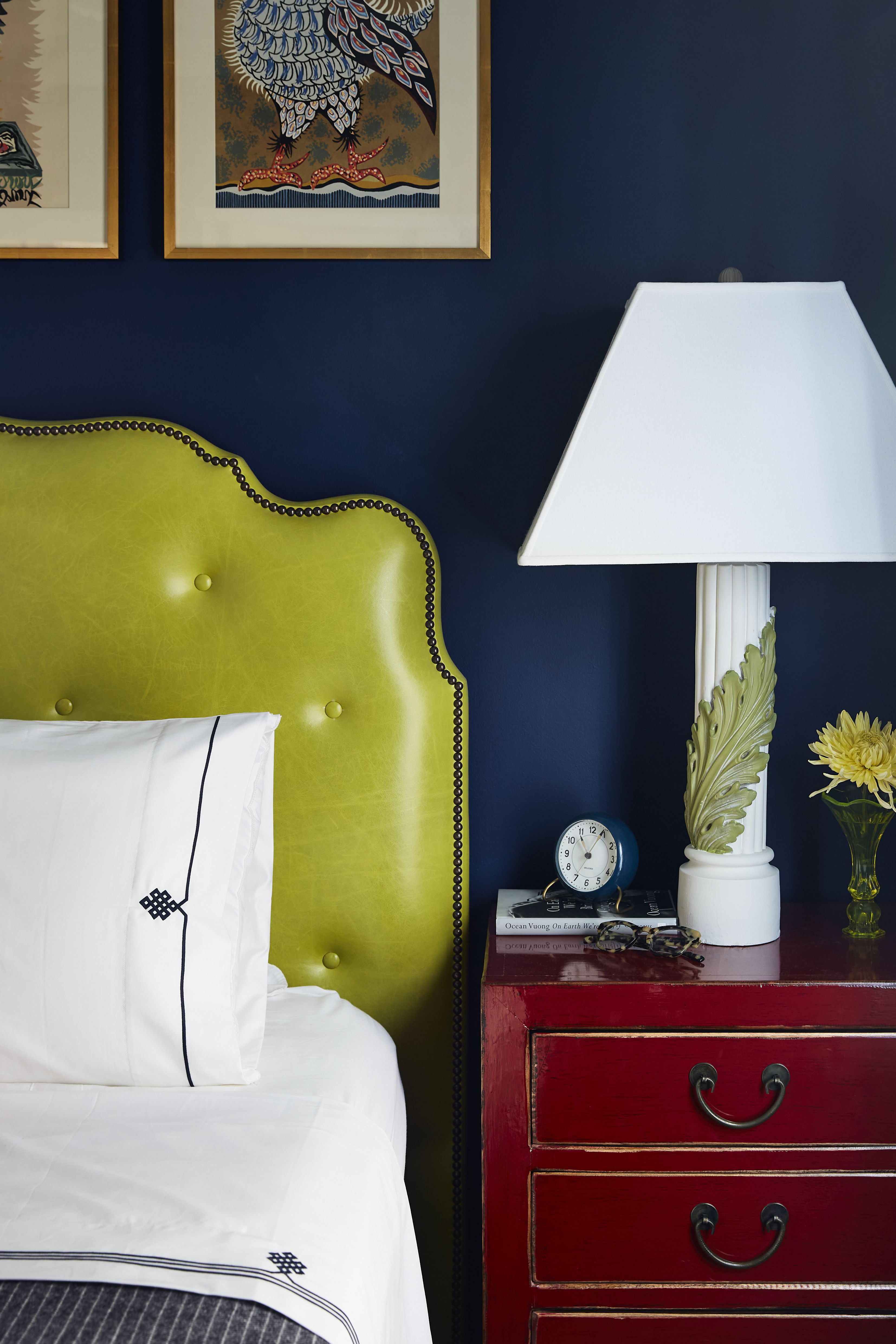 Navy blue bedroom featuring a chartreuse tufted leather heaboard and cherry wood nightstand