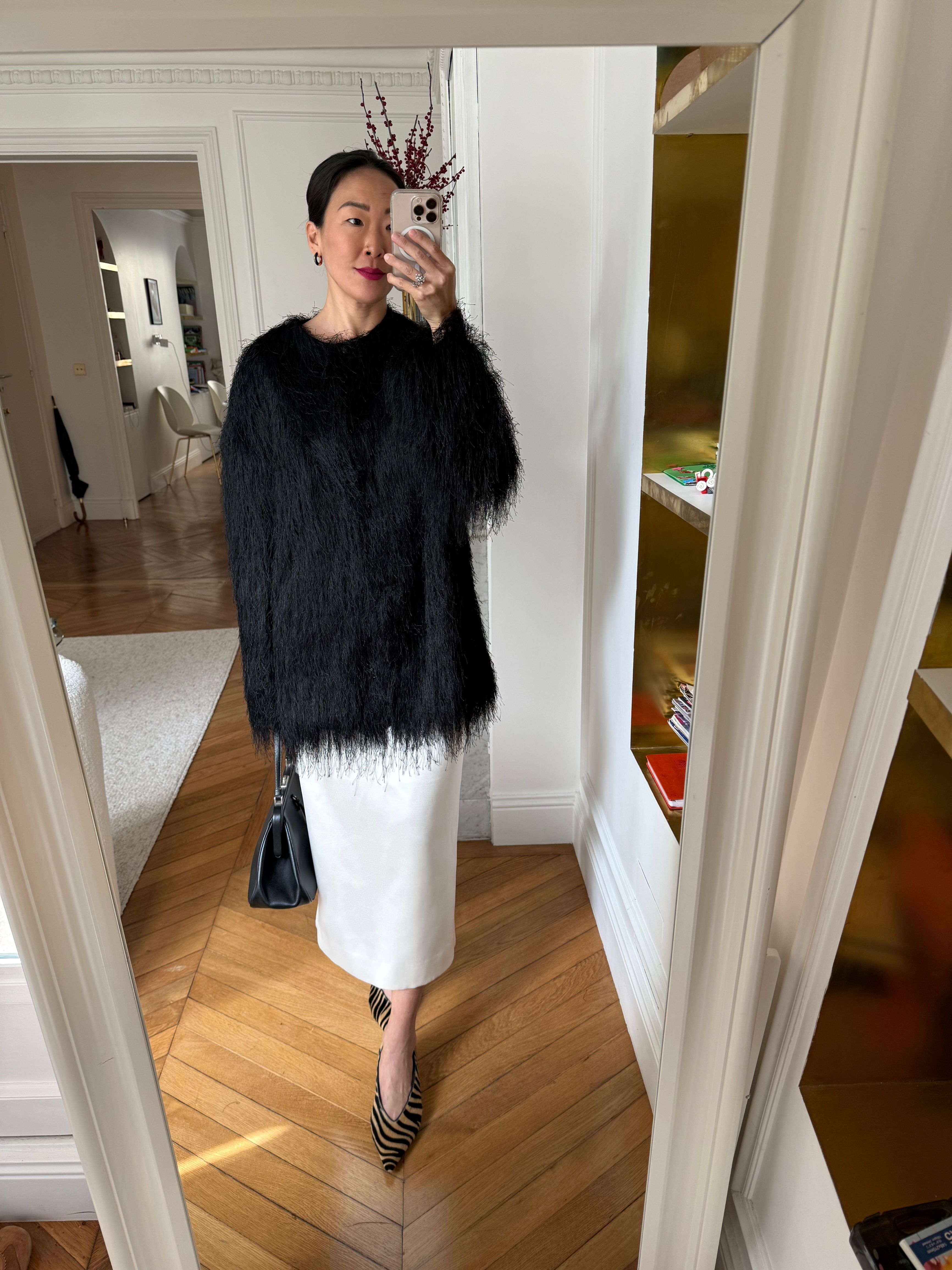 Irene Kim styles a black fringe coat with a white column skirt and deep-V tiger-print shoes