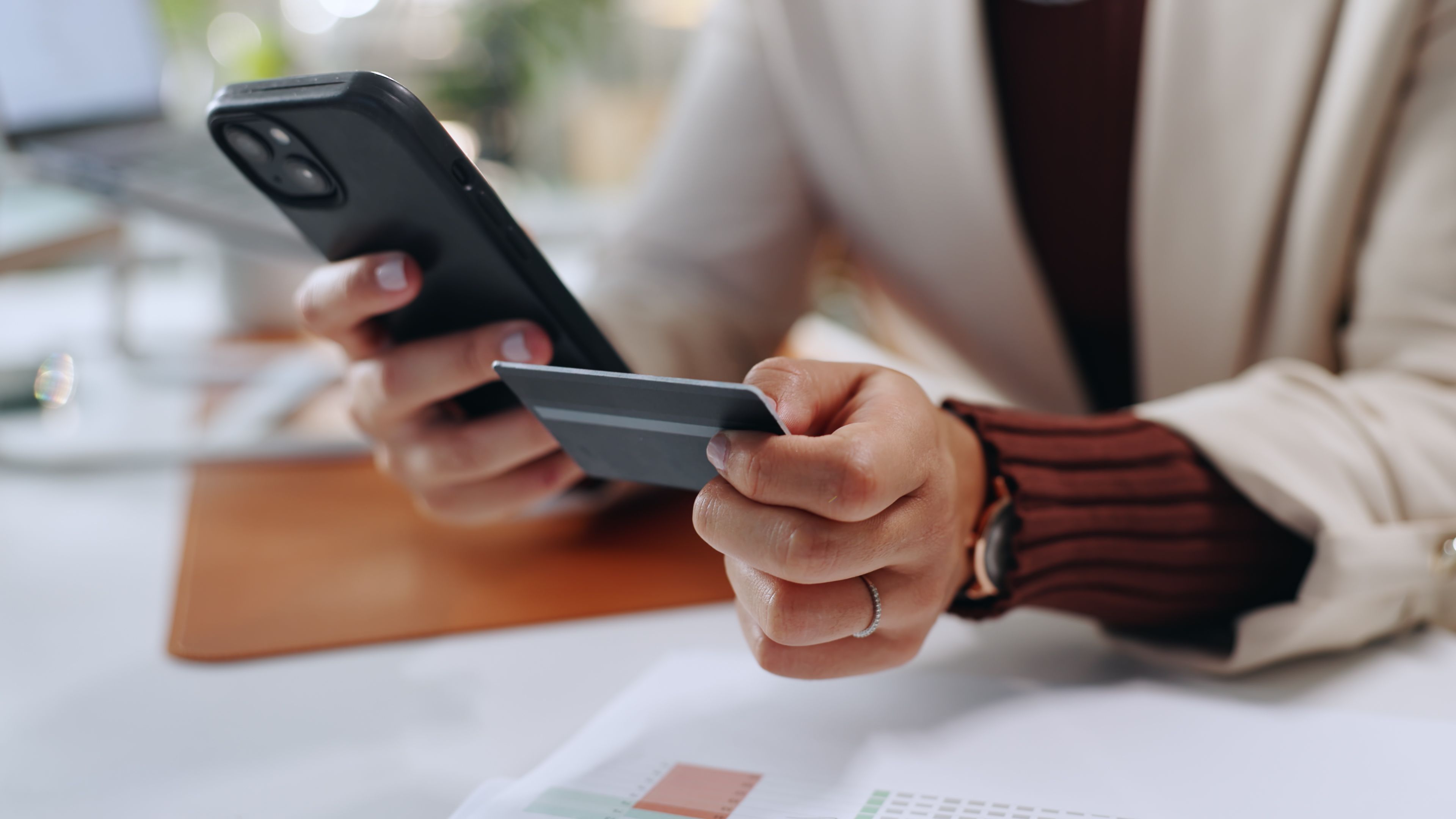 A person holding a credit card and a cell phone