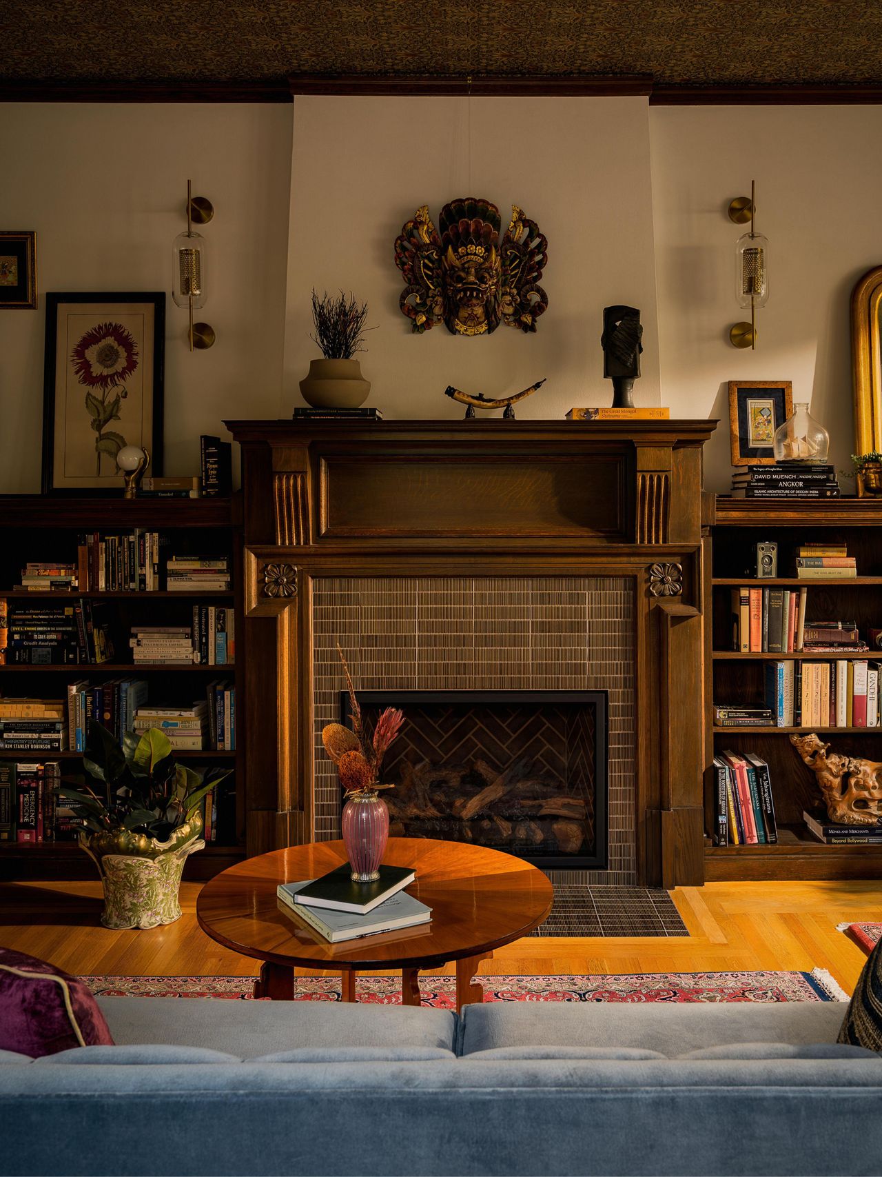 a moody home library with a wallpapered ceiling and original tudor fireplace